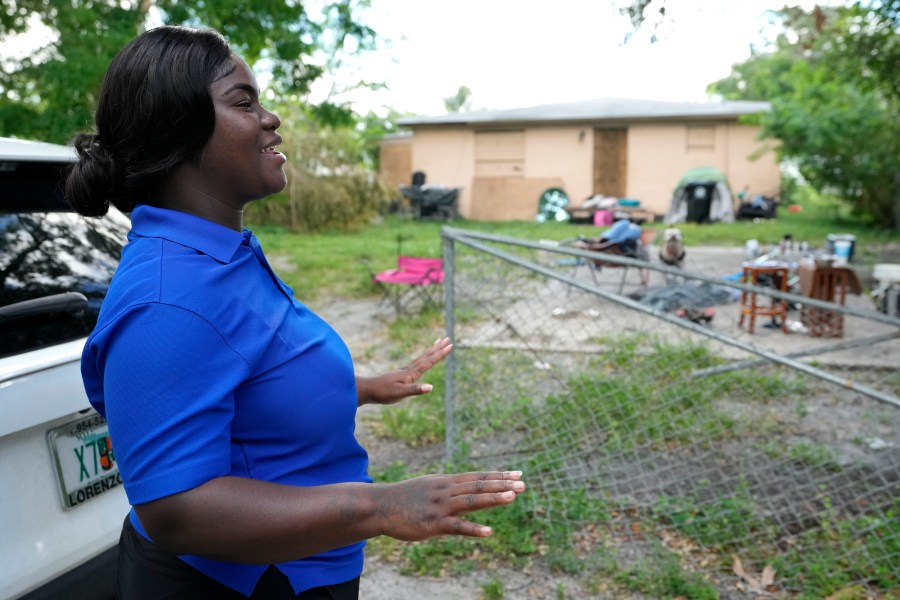 Erica Dorsett, program director of the TaskForce Fore Ending Homelessness, speaks with homeless people near an abandoned home on the first day of a statute that took effect, making it illegal in Florida to sleep on sidewalks, in parks, on beaches or in other public spaces — one of the country's strictest anti-homelessness laws, Tuesday, Oct. 1, 2024, in Fort Lauderdale, Fla. (AP Photo/Lynne Sladky)