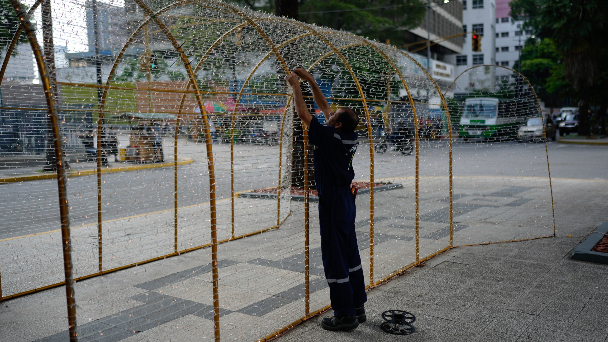 A worker sets up Christmas lights in Caracas, Venezuela, Tuesday, Oct. 1, 2024. (AP Photo/Ariana Cubillos)