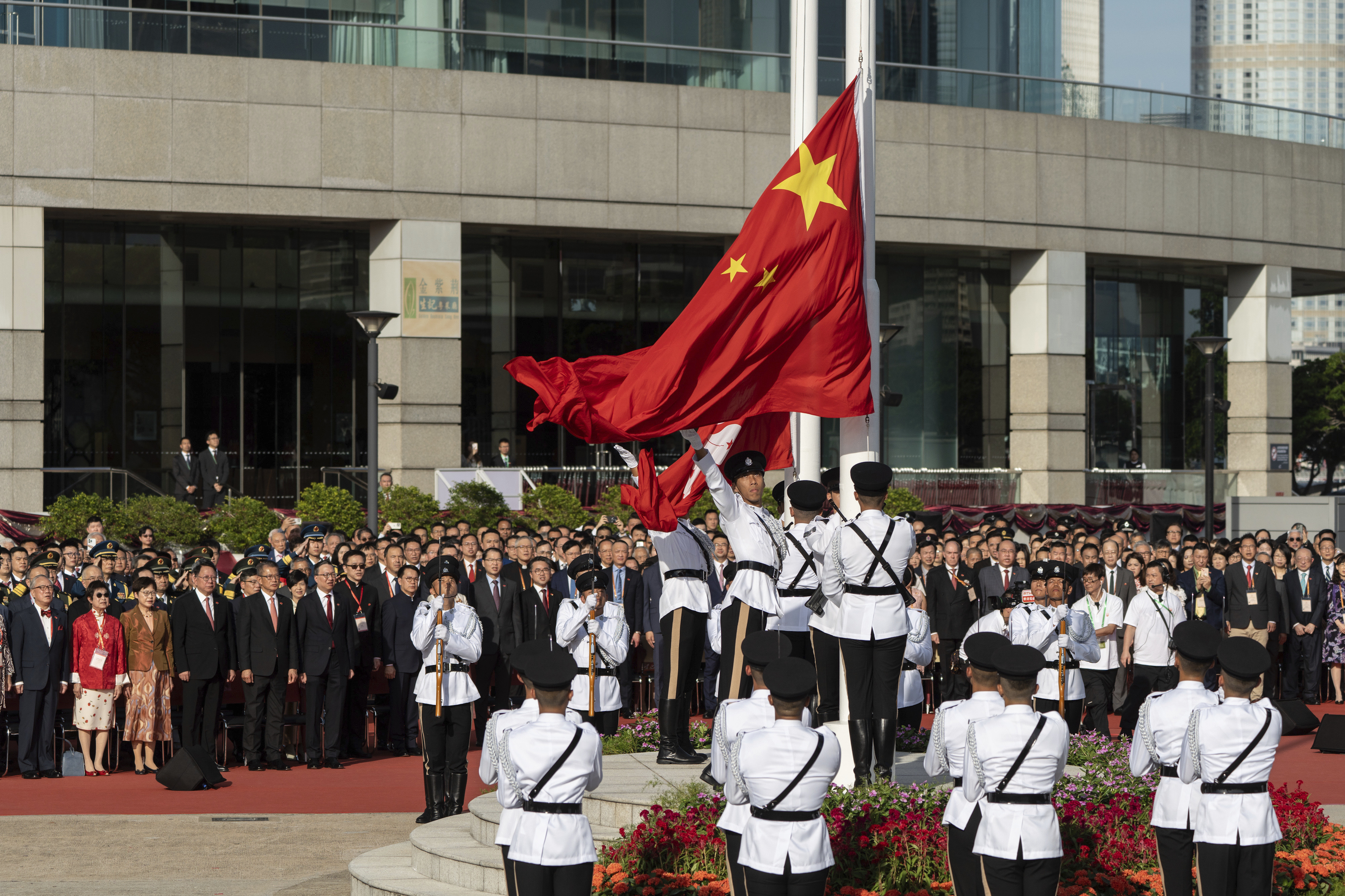 A Hong Kong police guard of honor rises China and Hong Kong flags during a flag raising ceremony for the celebration of the 75th National Day of the People's Republic of China in Hong Kong, Tuesday, Oct. 1, 2024. (AP Photo/Chan Long Hei)