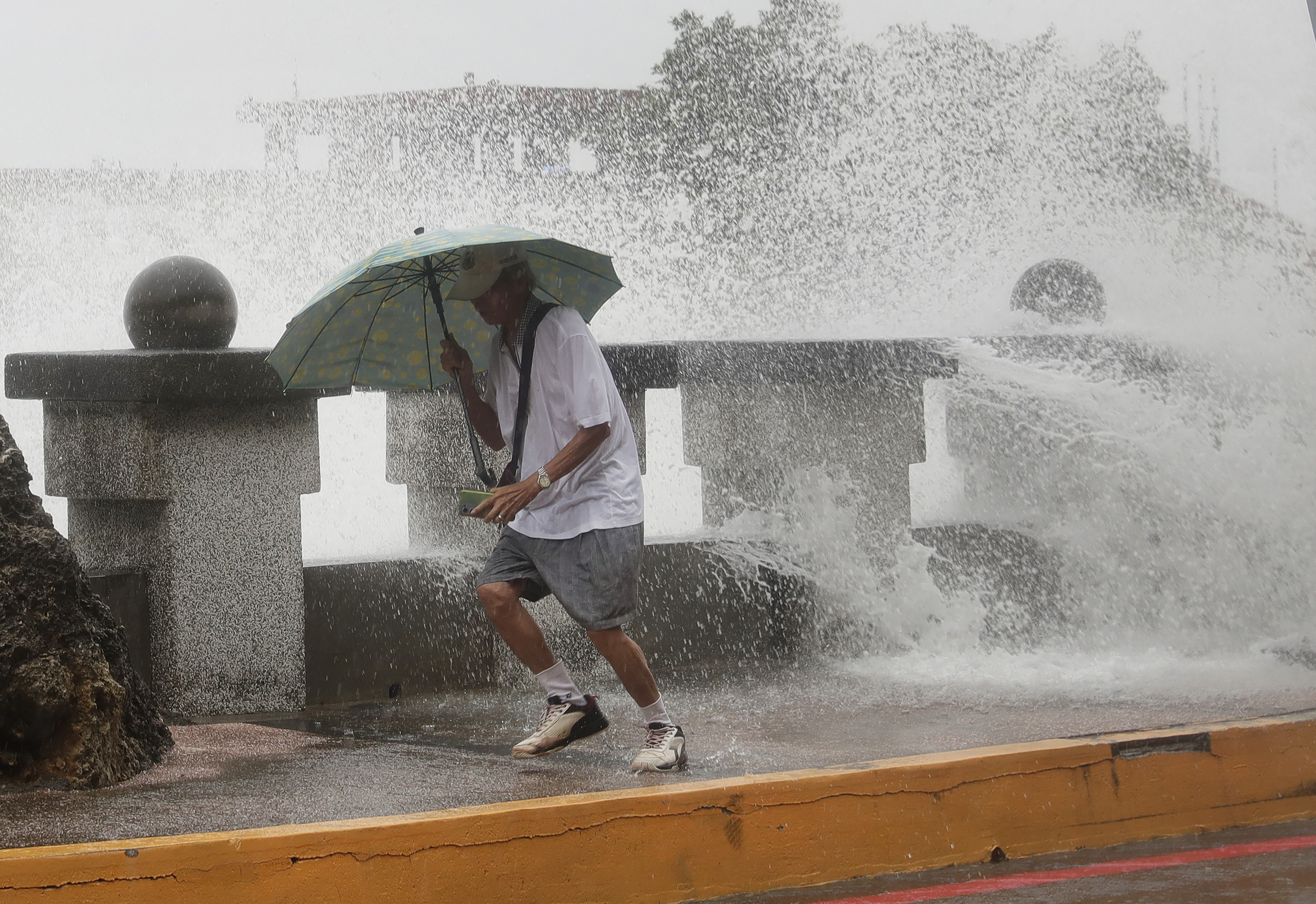 A man runs away from waves when he was walking along the shore in Kaohsiung, Southern Taiwan, Wednesday, Oct. 2, 2024, as Typhoon Krathon is expected to hit the area. (AP Photo/Chiang Ying-ying)