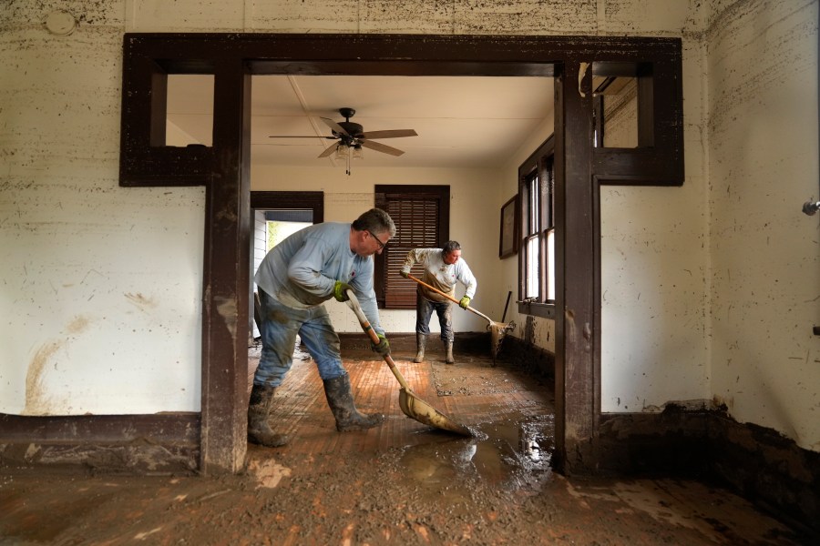 FILE - Ben Phillips, left, and his wife Becca Phillips scrape mud out of the living room of their home left in the wake of Hurricane Helene, Oct. 1, 2024, in Marshall, N.C. (AP Photo/Jeff Roberson, File)