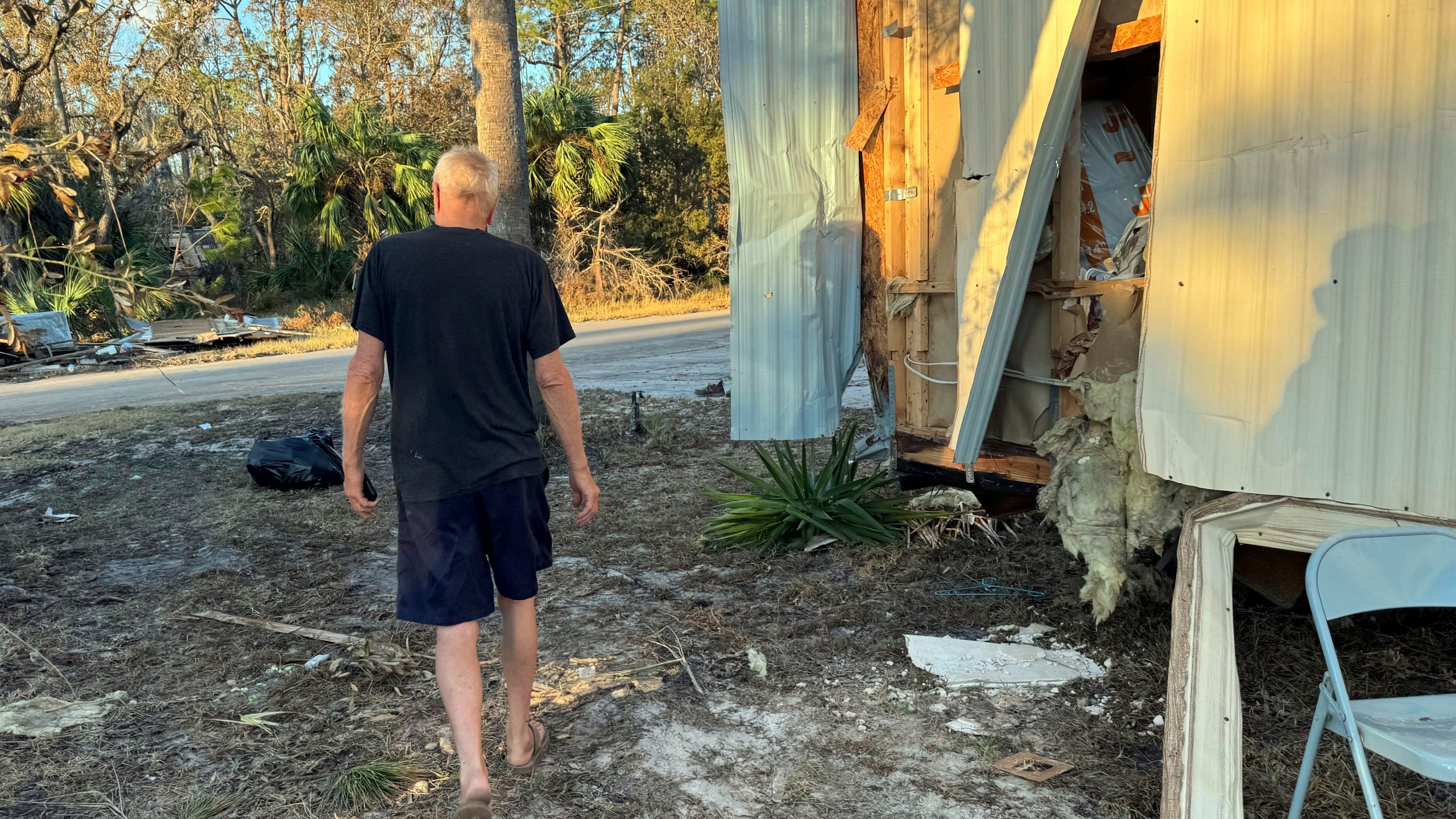 Dave Beamer walks past the partially destroyed trailer he's been living in, Sunday, Sept. 29, 2024, in Steinhatchee, Fla., after Hurricane Helene washed his home into a marsh. (AP Photo/Kate Payne)