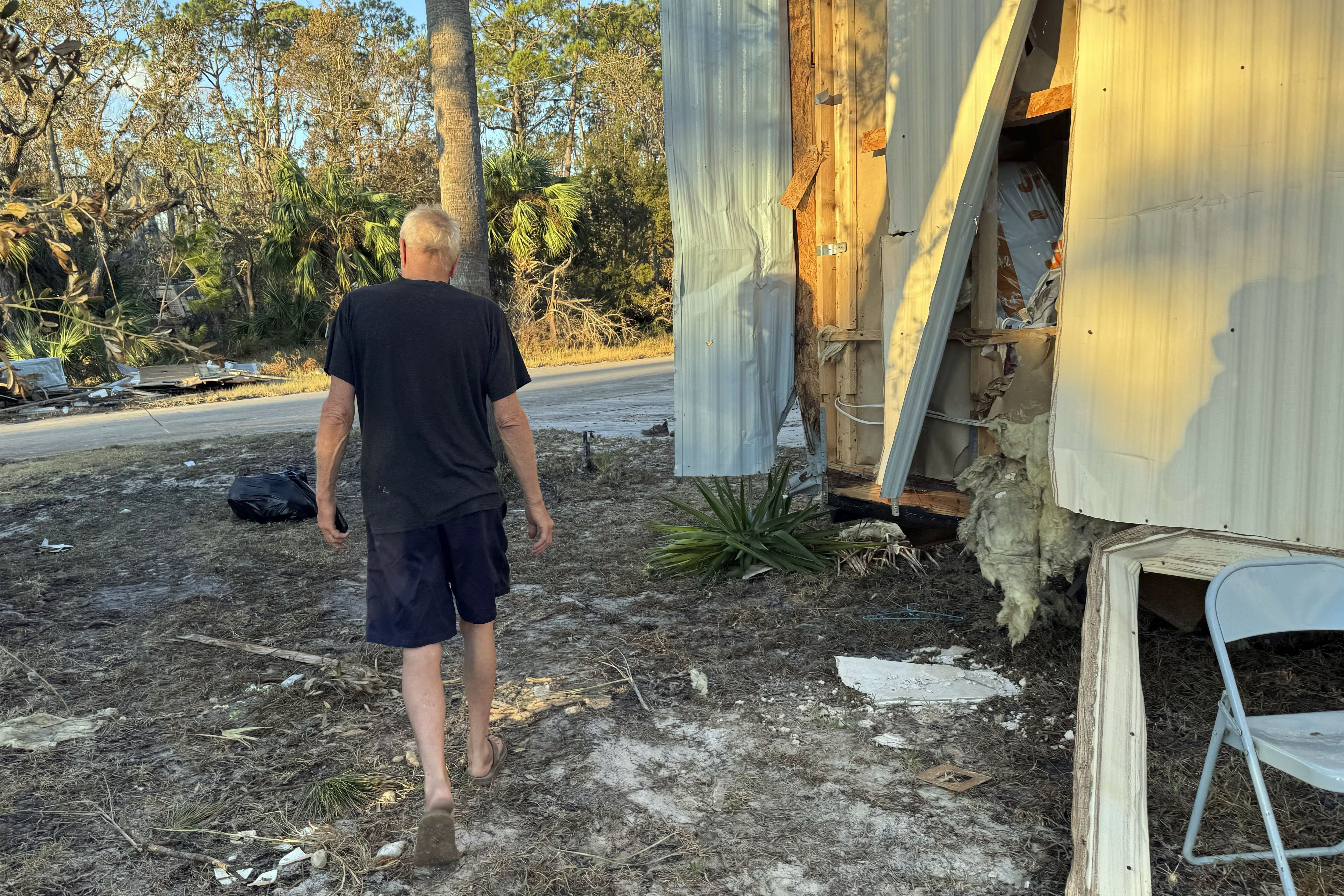 Dave Beamer walks past the partially destroyed trailer he's been living in, Sunday, Sept. 29, 2024, in Steinhatchee, Fla., after Hurricane Helene washed his home into a marsh. (AP Photo/Kate Payne)