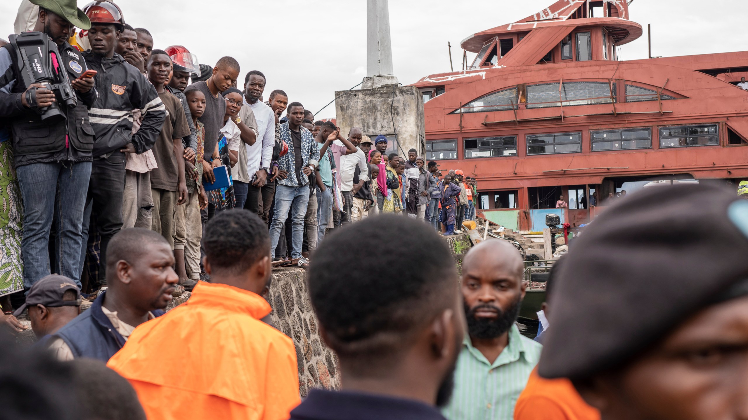 People gather at the port of Goma, Democratic Republic of Congo, after a ferry carrying hundreds capsized on arrival Thursday, Oct. 3, 2024, killing scores. (AP Photo/Moses Sawasawa)