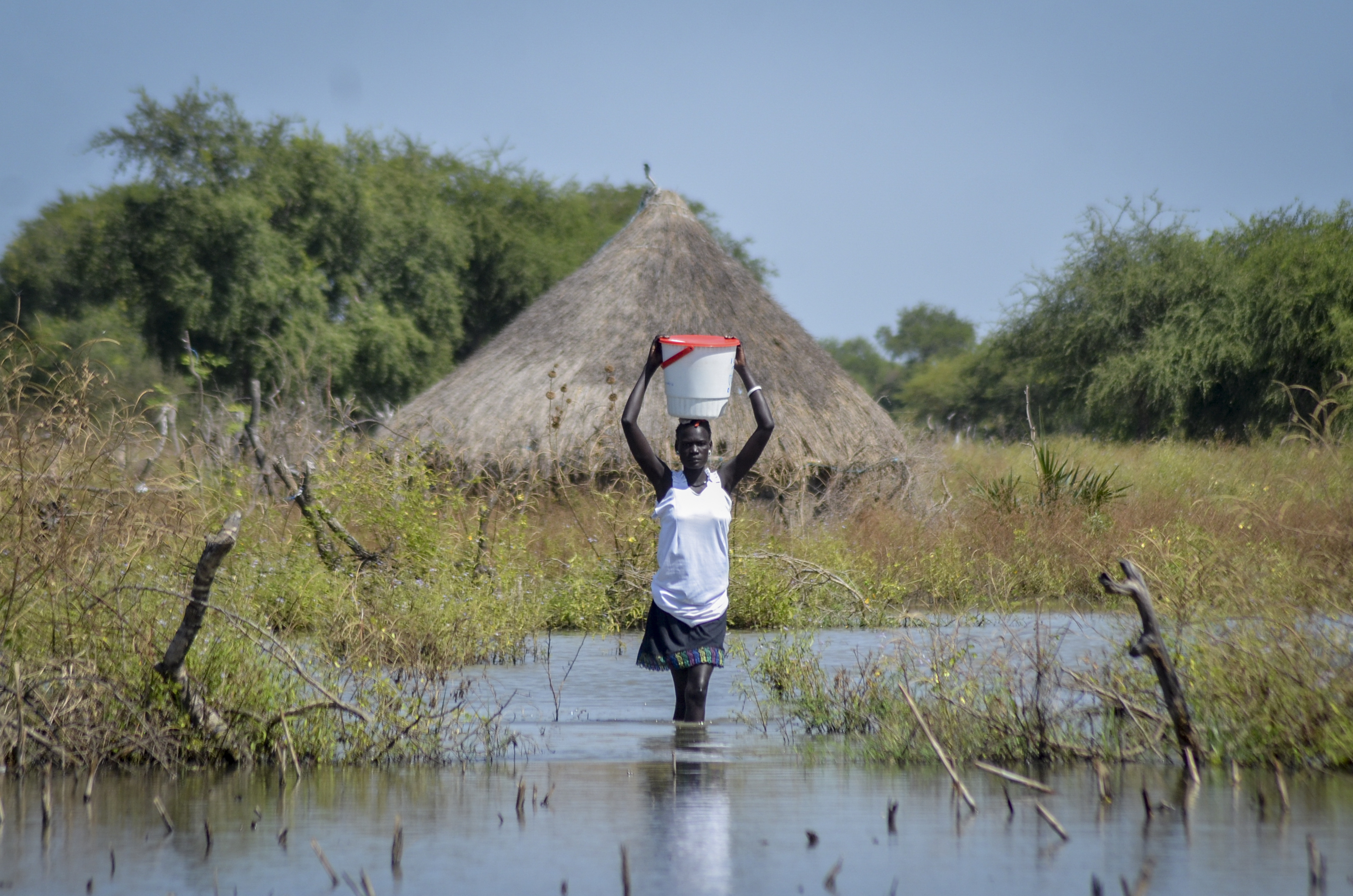 FILE - A woman carries a bucket on her head as she wades through floodwaters in the village of Wang Chot, Old Fangak county, Jonglei state, South Sudan, on Nov. 26, 2020. (AP Photo/Maura Ajak, File)