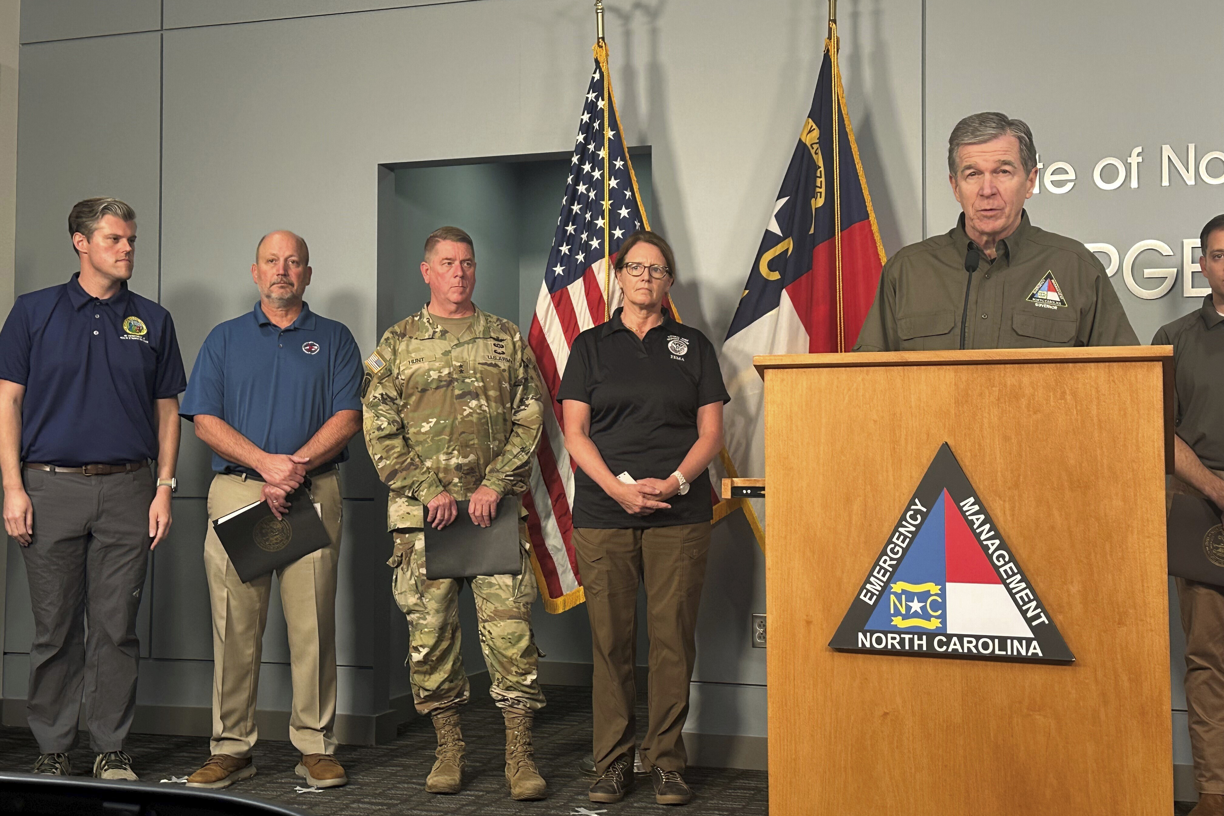 North Carolina Gov. Roy Cooper, right at podium, speaks during a media briefing on the government response to Hurricane Helene in western North Carolina while Federal Emergency Management Agency Administrator Deanne Criswell, center, and others listen at the state Emergency Operations Center in Raleigh, N.C., Tuesday, Oct. 1, 2024. (AP Photo/Gary D. Robertson)