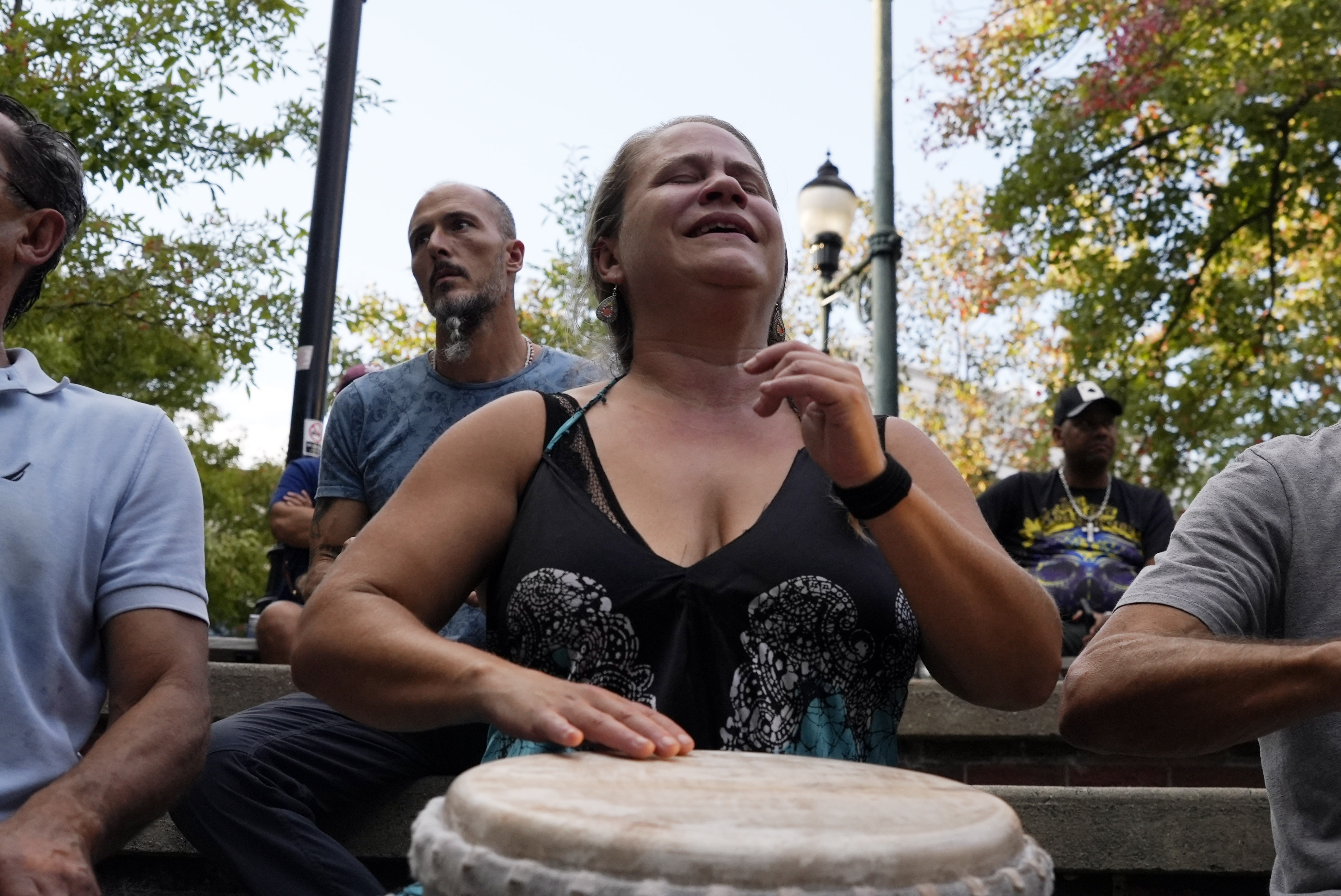 A woman plays music at a drum circle Friday, Oct. 4, 2024 in Asheville, N.C., a week after Hurricane Helene upended lives across the Southeast. (AP Photo/Brittany Peterson)