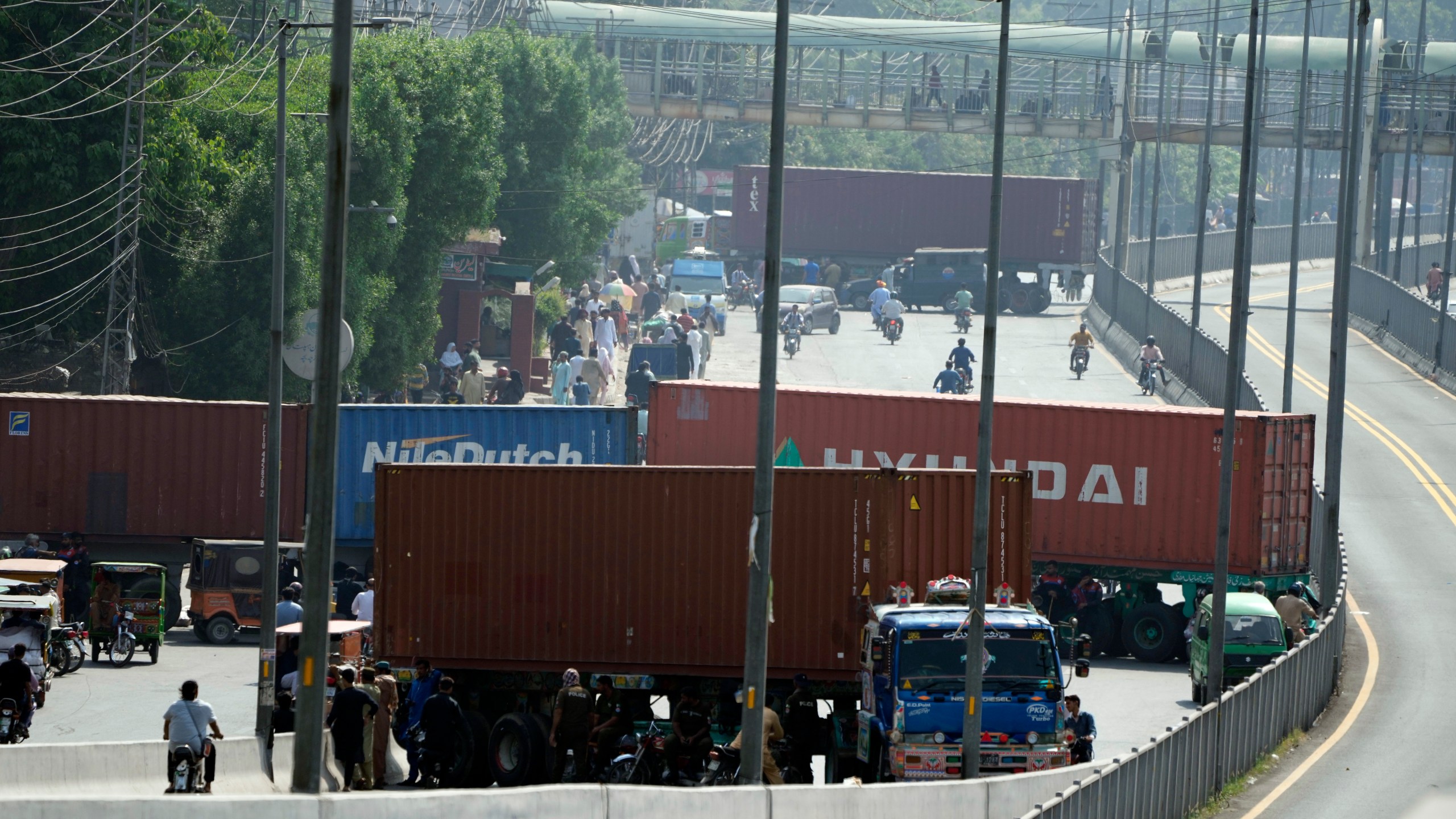 Shipping containers set up by authorities block a road, preventing the supporters of imprisoned former Prime Minister Imran Khan from holding a rally to demand his release in Lahore, Pakistan, Saturday, Oct. 5, 2024. (AP Photo/K.M. Chaudary)