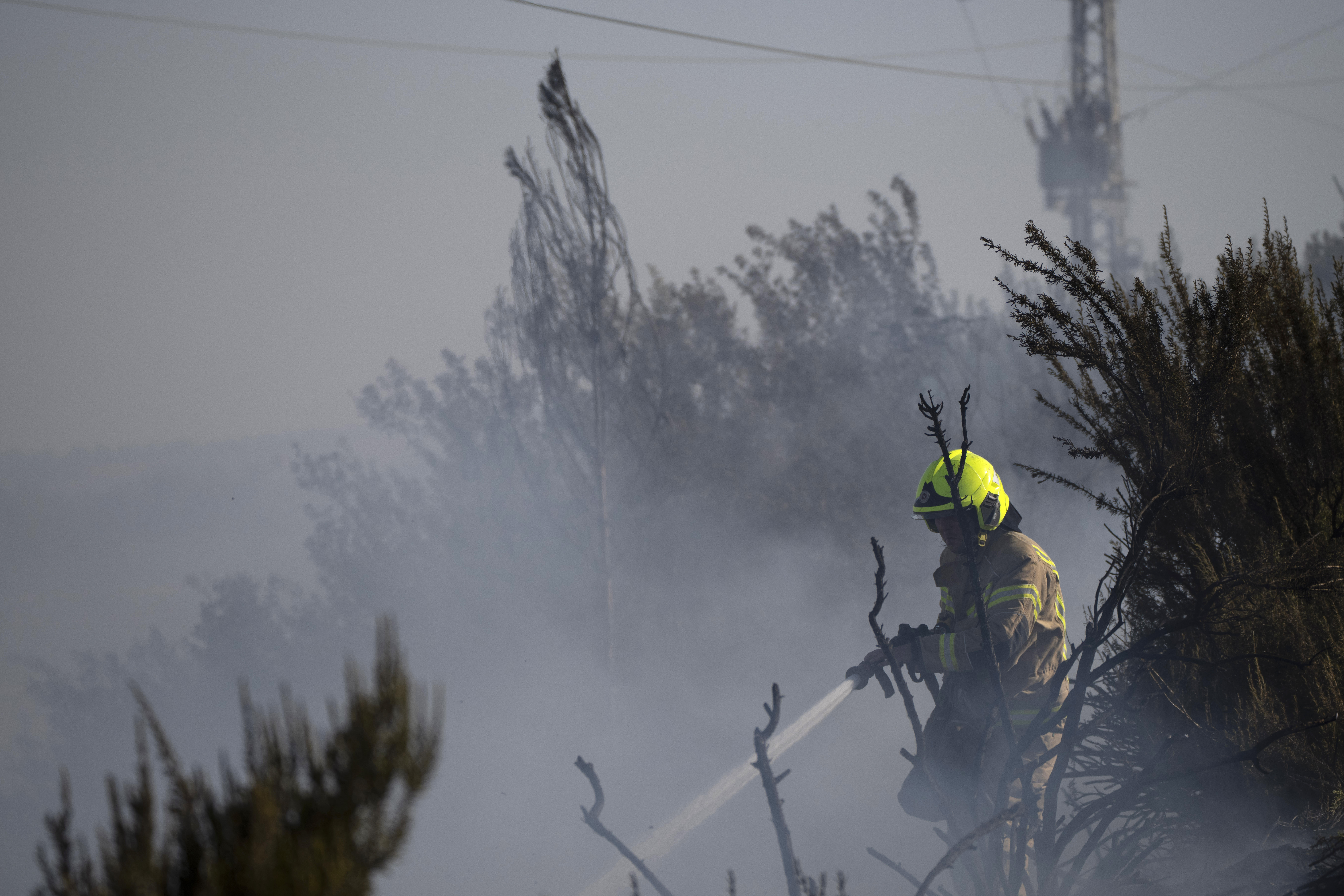 A firefighter works to extinguish a fire after a rocket, fired from Lebanon, hit an area next to a road near Kiryat Shmona, northern Israel, Saturday, Oct. 5, 2024. (AP Photo/Leo Correa)