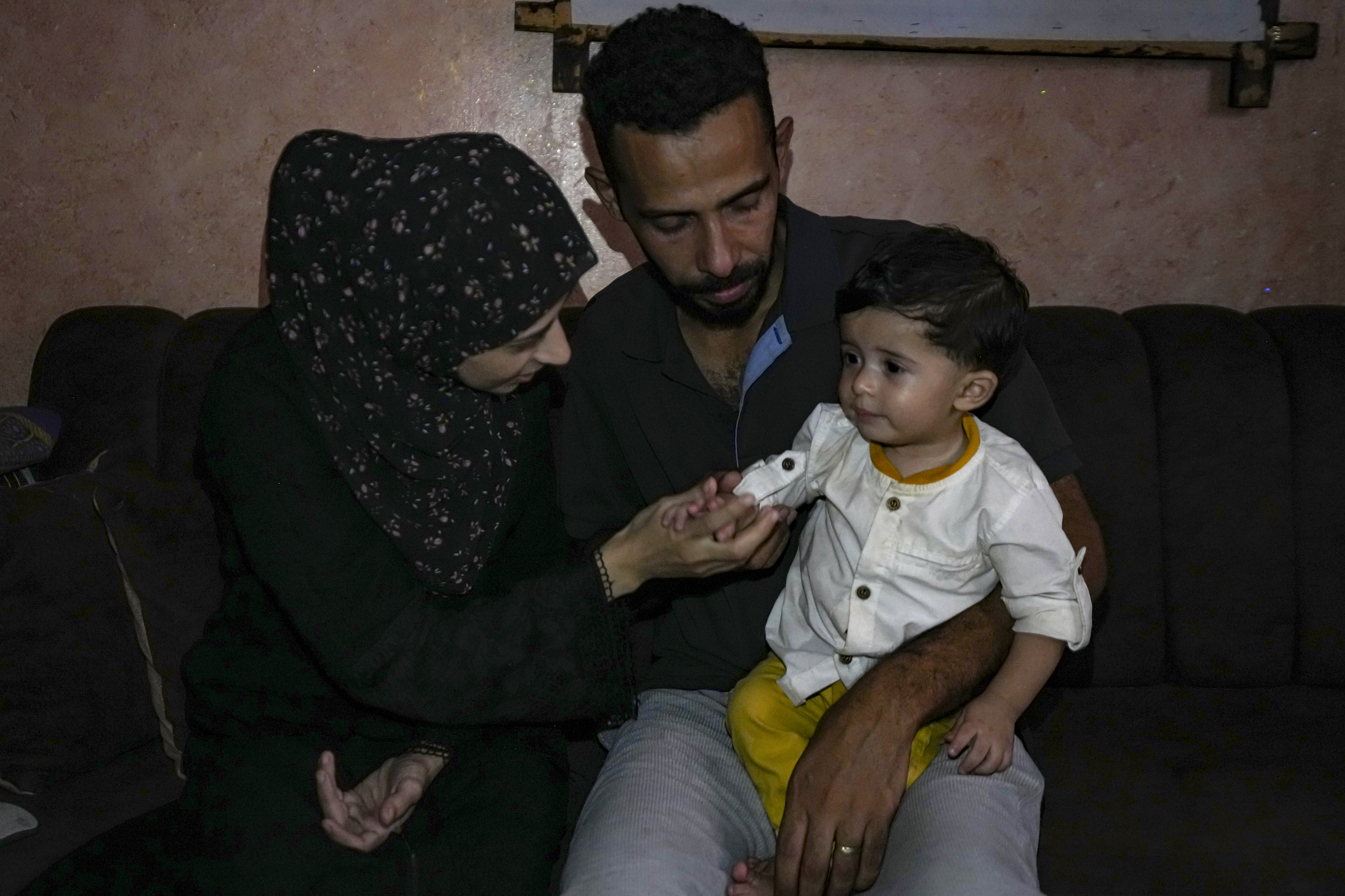 Amal and Mustafa Al-Taweel play with their child Ali, who was born on October 7, at their home in Nuseirat, as the Israeli-Hamas war marks its one year anniversary, Gaza Strip, Saturday, Oct. 5, 2024. (AP Photo/Abdel Kareem Hana)