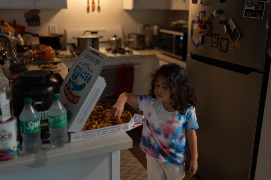 Rubie Caceres, a granddaughter of Marina Maalouf, a longtime resident of Hillside Villa, grabs a slice of pizza in her apartment in Los Angeles, Tuesday, Oct. 1, 2024. (AP Photo/Jae C. Hong)