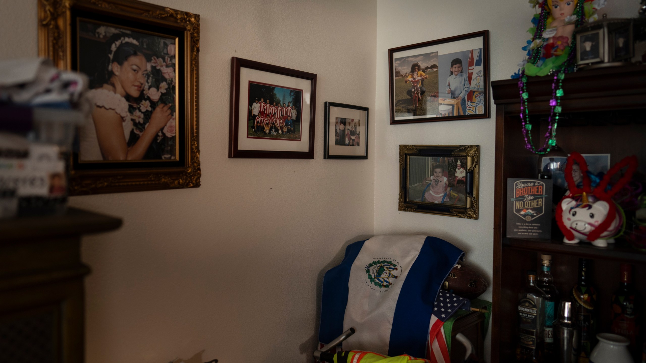 A wall in Marina Maalouf's apartment is adorned with family photos as an El Salvadoran flag is draped over an American flag in Los Angeles, Tuesday, Oct. 1, 2024. (AP Photo/Jae C. Hong)