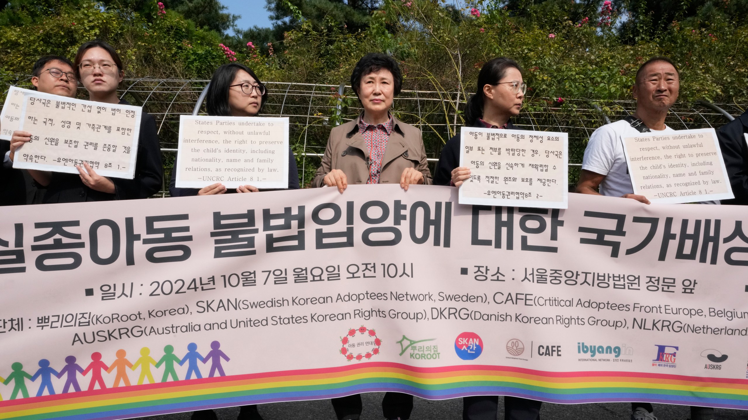 Han Tae-soon, center, attends a press conference in front of the Seoul Central District Court in Seoul, South Korea, Monday, Oct. 7, 2024 before she sues her government, an adoption agency and an orphanage over the adoption of her daughter. The banner reads "Lawsuit for state compensation on the illegal adoption of a missing child." (AP Photo/Ahn Young-joon)