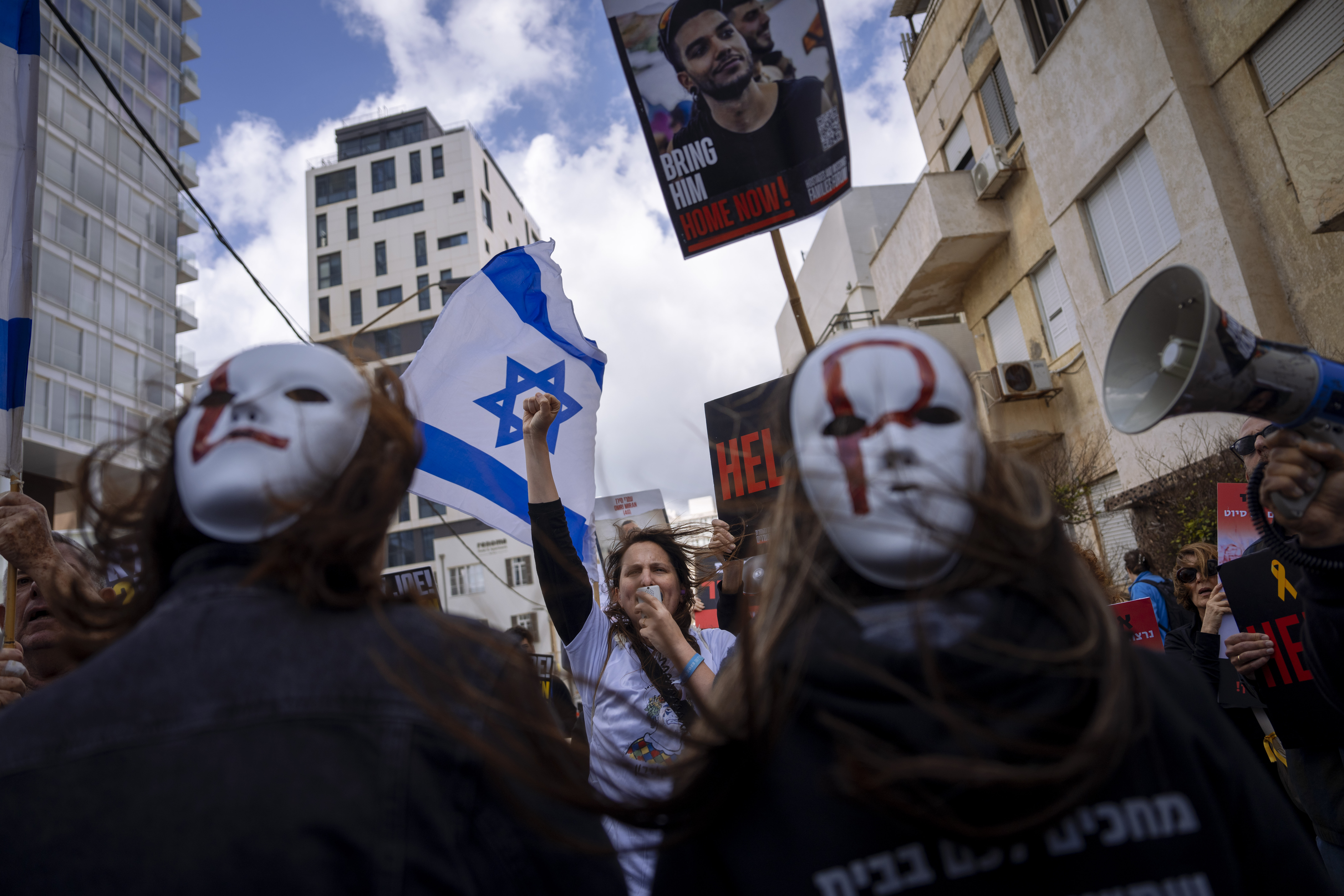 Families and supporters of Israeli hostages held by Hamas in Gaza wave photos of their loved ones and the Israeli and U.S. flags during a protest calling for their return, outside a meeting between U.S. Secretary of State Antony Blinken and families of hostages, in Tel Aviv, Israel, Friday, March 22, 2024. (AP Photo/Oded Balilty)