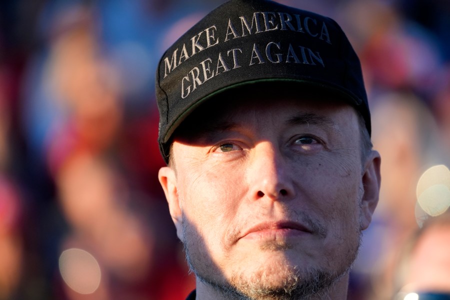 Tesla and SpaceX CEO Elon Musk listens as Republican presidential nominee former President Donald Trump speaks at a campaign event at the Butler Farm Show, Saturday, Oct. 5, 2024, in Butler, Pa. (AP Photo/Alex Brandon)