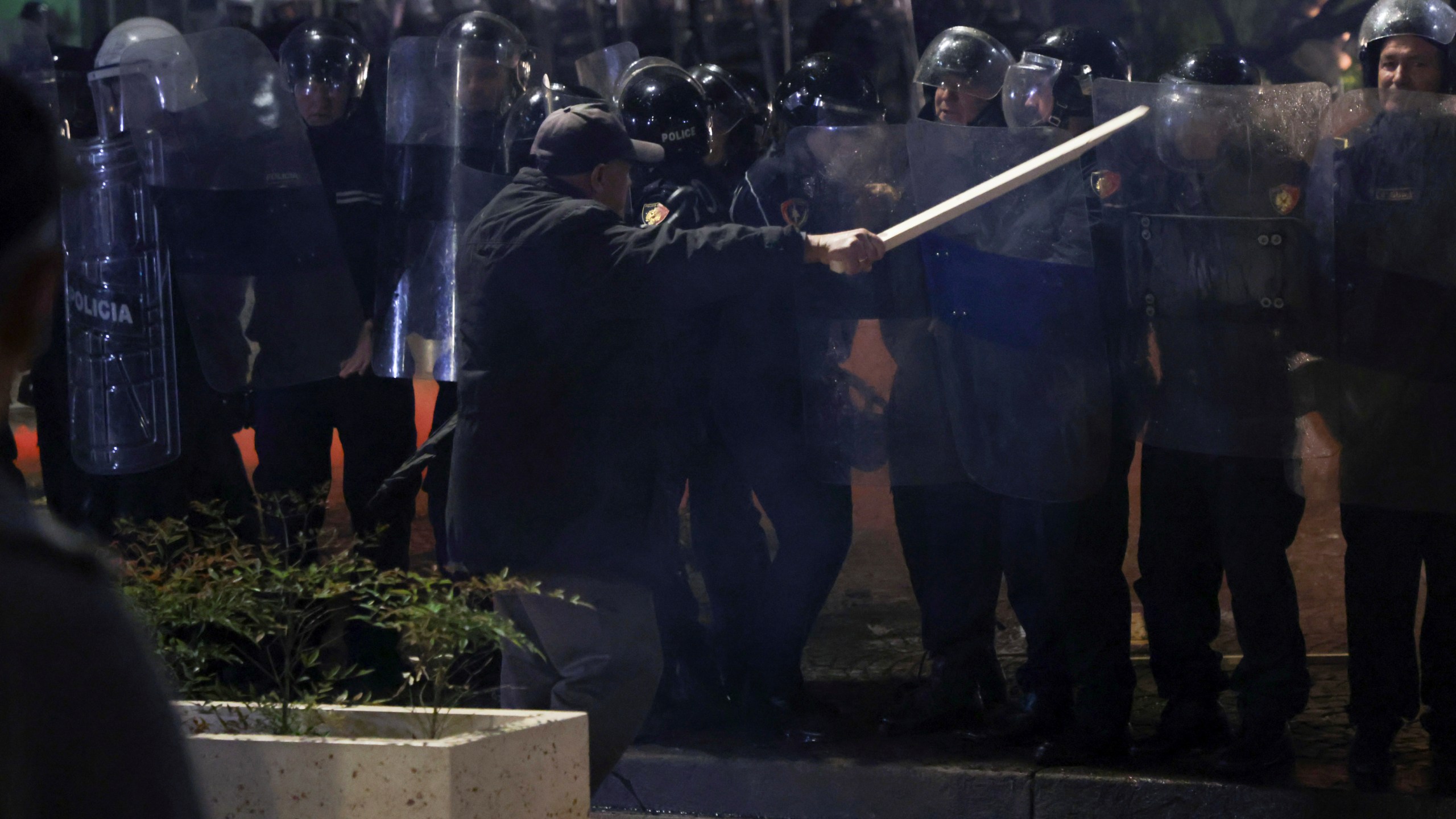 An opposition supporter waves a wooden stick to riot police during a anti-government rally, in Tirana, Albania, Monday, Oct. 7, 2024. (AP Photo/Hameraldi Agolli)