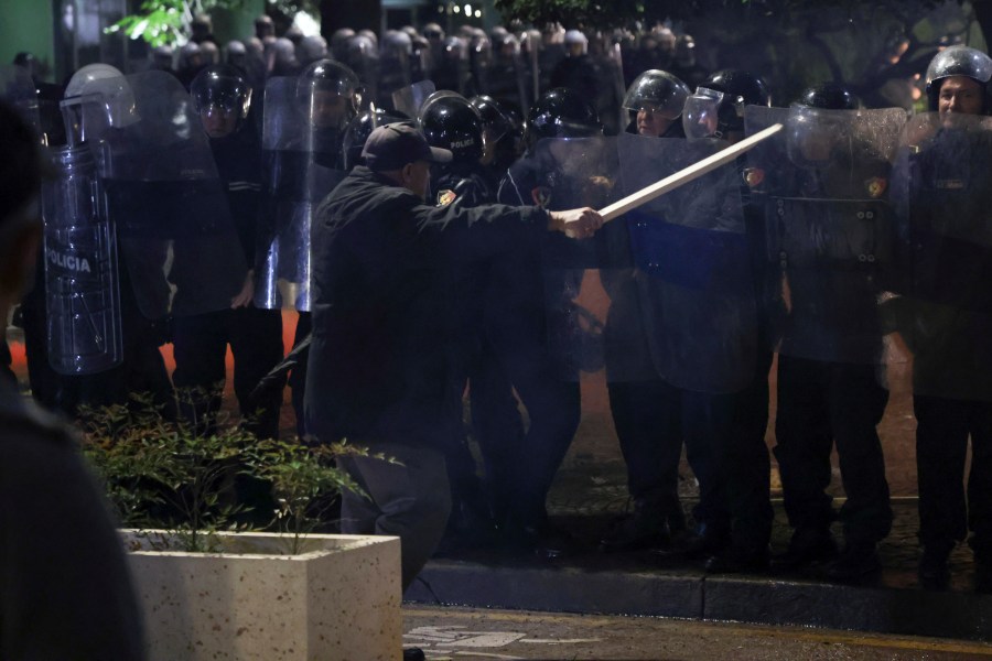 An opposition supporter waves a wooden stick to riot police during a anti-government rally, in Tirana, Albania, Monday, Oct. 7, 2024. (AP Photo/Hameraldi Agolli)