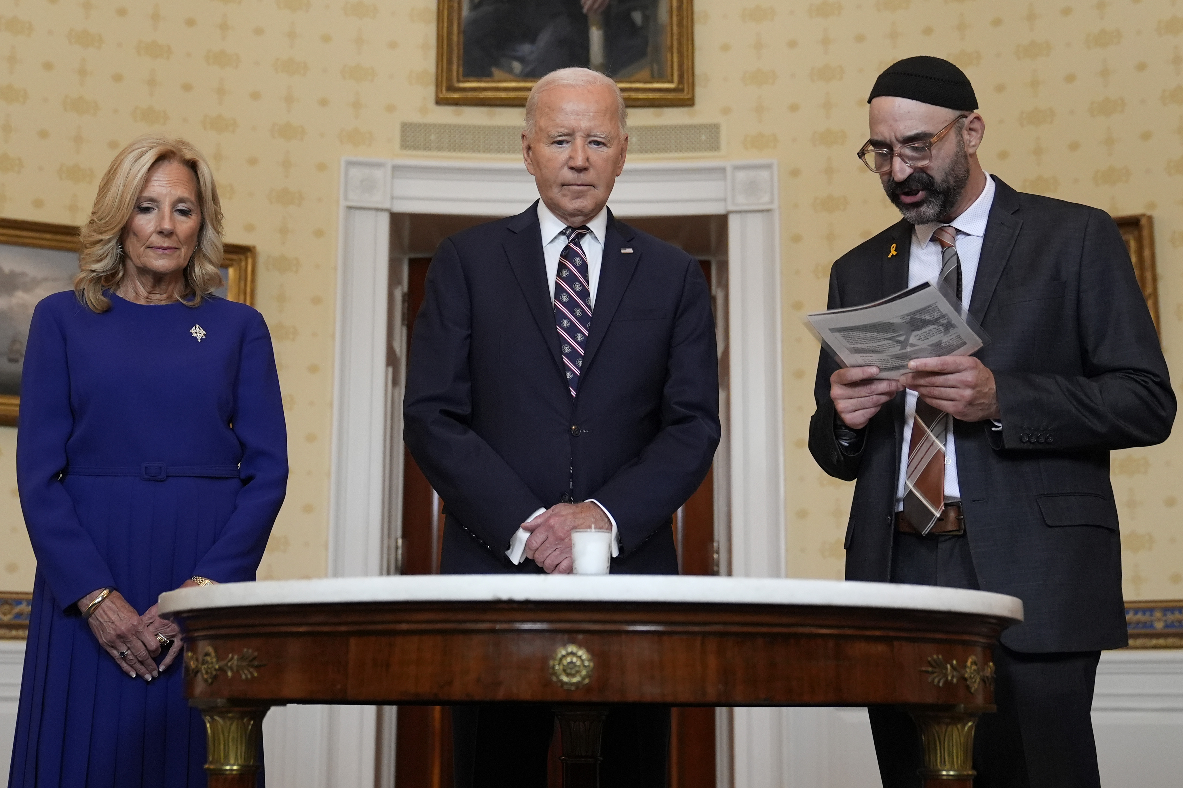 President Joe Biden, center, standing with first lady Jill Biden, left, and Rabbi Aaron Alexander of the Adas Israel Congregation, participates in a memorial candle-lighting in the Blue Room of the White House in Washington, Monday, Oct. 7, 2024, to mark the one-year anniversary of the Hamas attack on Israel that left about 1,200 people dead. (AP Photo/Susan Walsh)