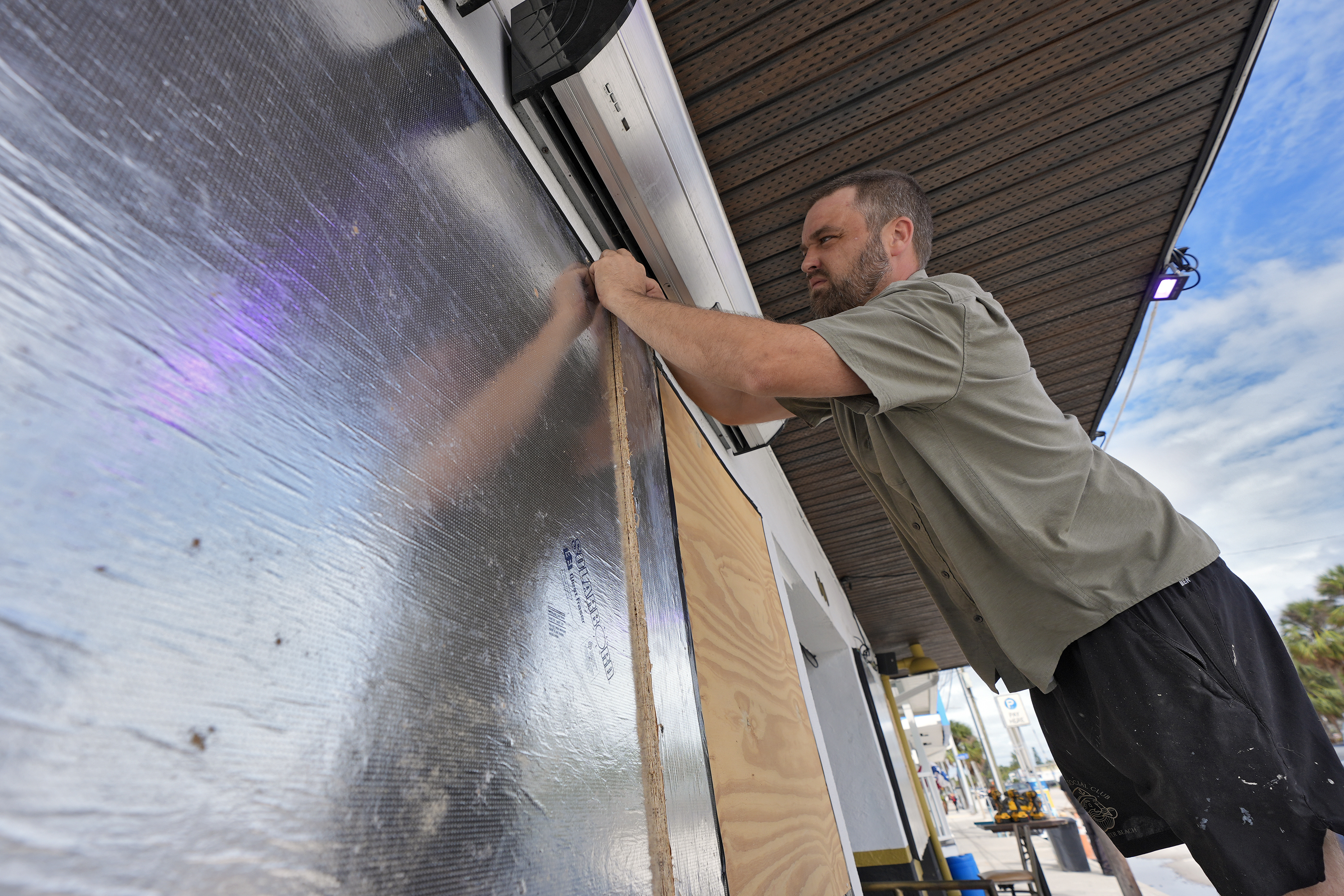 Rob Menard, owner of Reefers Social Club, finishes putting up boards and tape over windows Monday, Oct. 7, 2024, in Clearwater Beach, Fla., ahead of the possible arrival of Hurricane Milton. (AP Photo/Chris O'Meara)