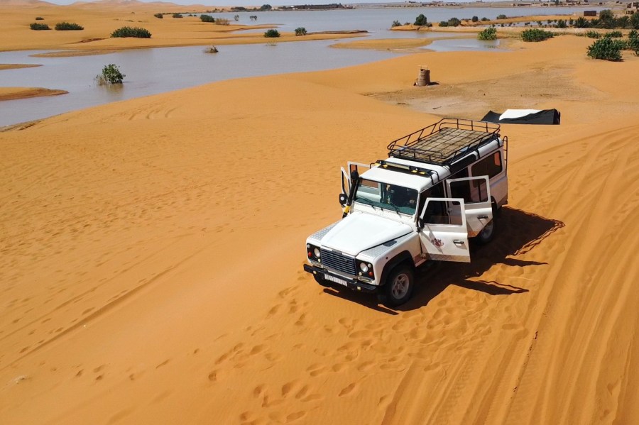 A vehicle transports tourists on sand dunes next to a lake caused by heavy rainfall in the desert town of Merzouga, near Rachidia, southeastern Morocco, Wednesday, Oct. 2, 2024. (AP Photo)