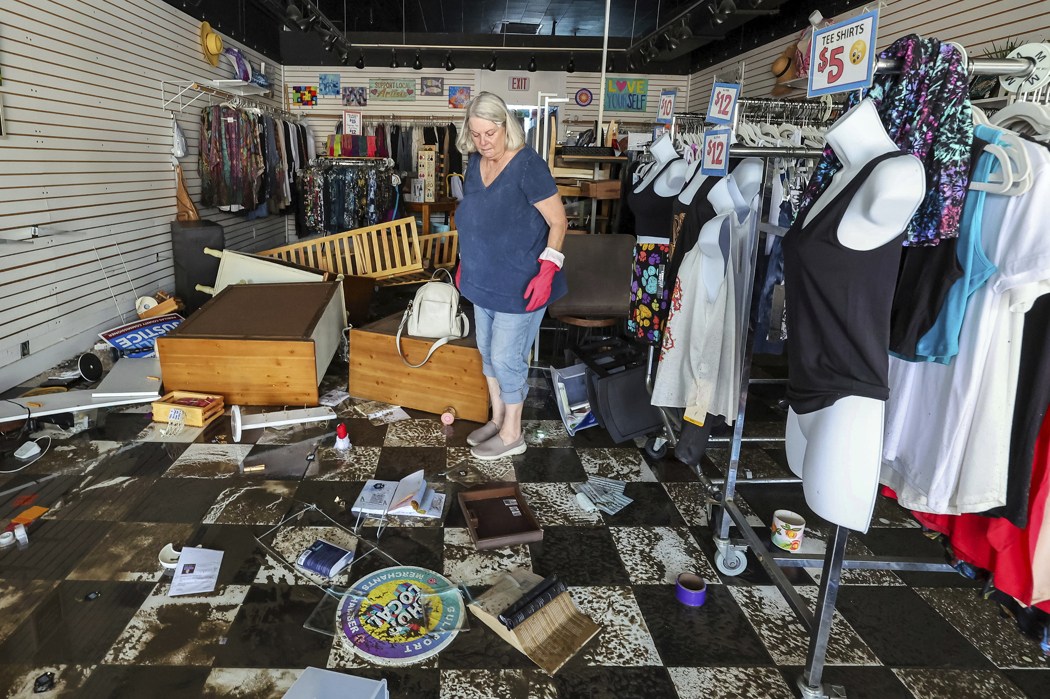 FILE - Jill Rice looks over the damage to her store caused by flooding from Hurricane Helene, Sept. 27, 2024, in Gulfport, Fla. (AP Photo/Mike Carlson, File)