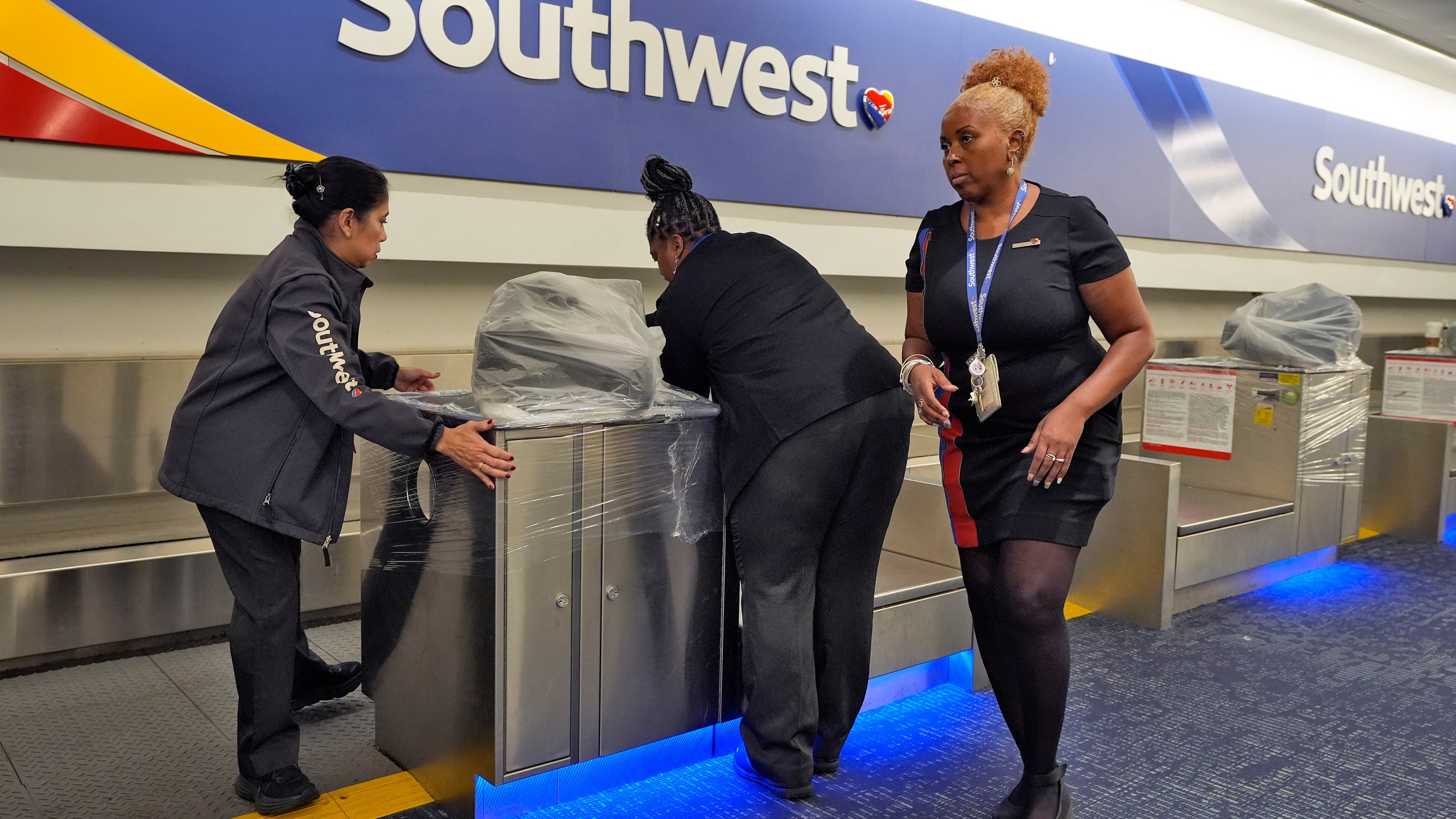 Southwest Airlines employees cover the ticket counters with plastic wrap just before Tampa International Airport was closing due to the possible arrival of Hurricane Milton Tuesday, Oct. 8, 2024, in Tampa, Fla. (AP Photo/Chris O'Meara)