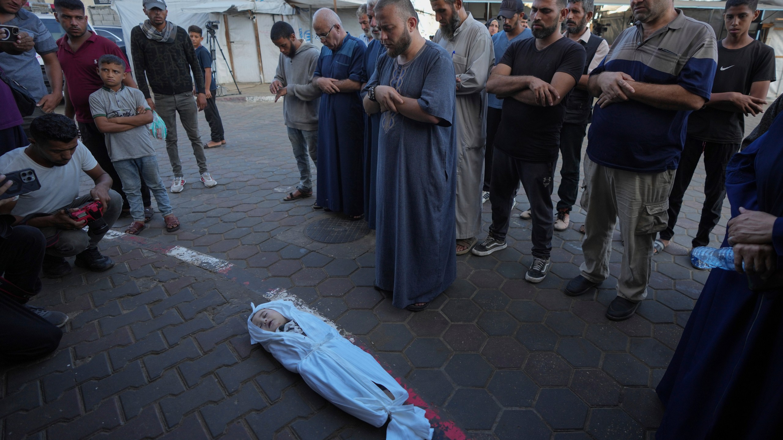 Mourners pray over the body of a Palestinian child, Hosam Al Khaldi, killed in the Israeli bombardment of the Gaza Strip outside the hospital morgue in Deir al-Balah on Wednesday, Oct. 9, 2024. (AP Photo/Abdel Kareem Hana)