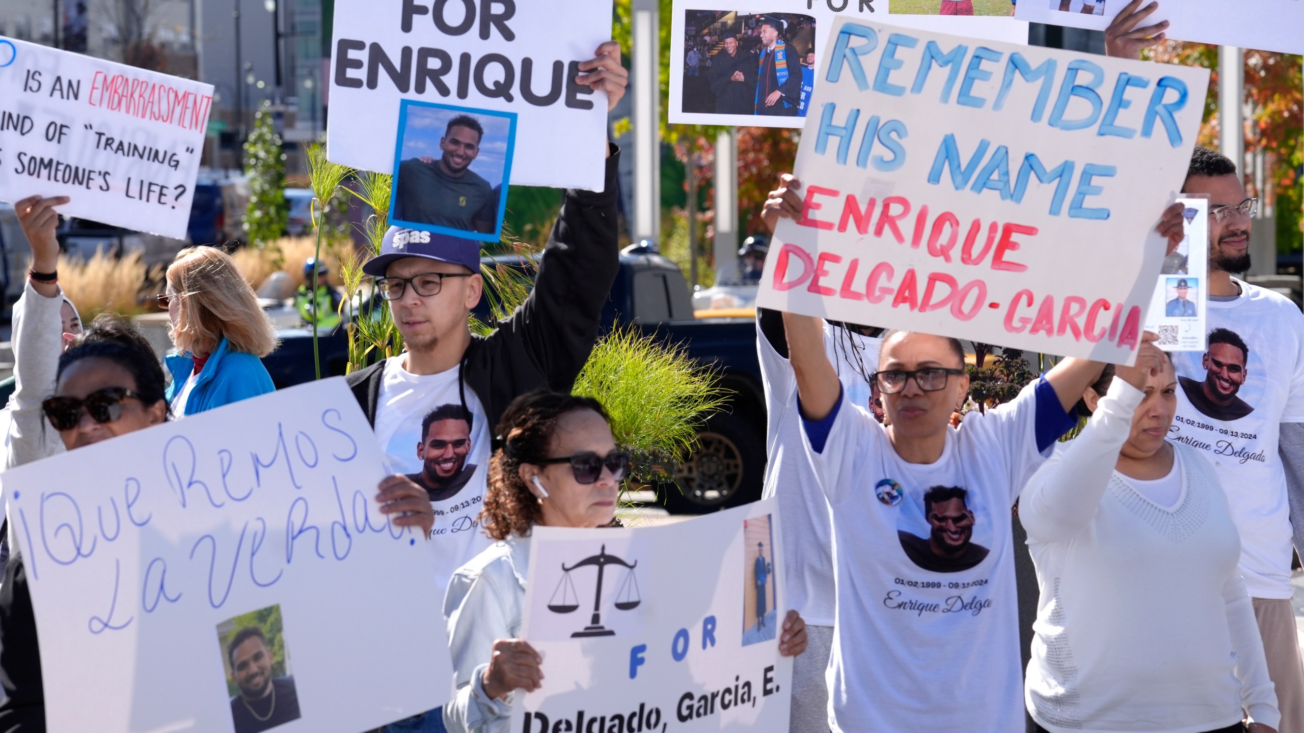 People display signs with with a likeness of Massachusetts State Police recruit Enrique Delgado-Garcia, who died following a State Police Academy training exercise, at a protest outside the State Police Academy graduation ceremony, Wednesday, Oct. 9, 2024, at the DCU Center, in Worcester, Mass. (AP Photo/Steven Senne)