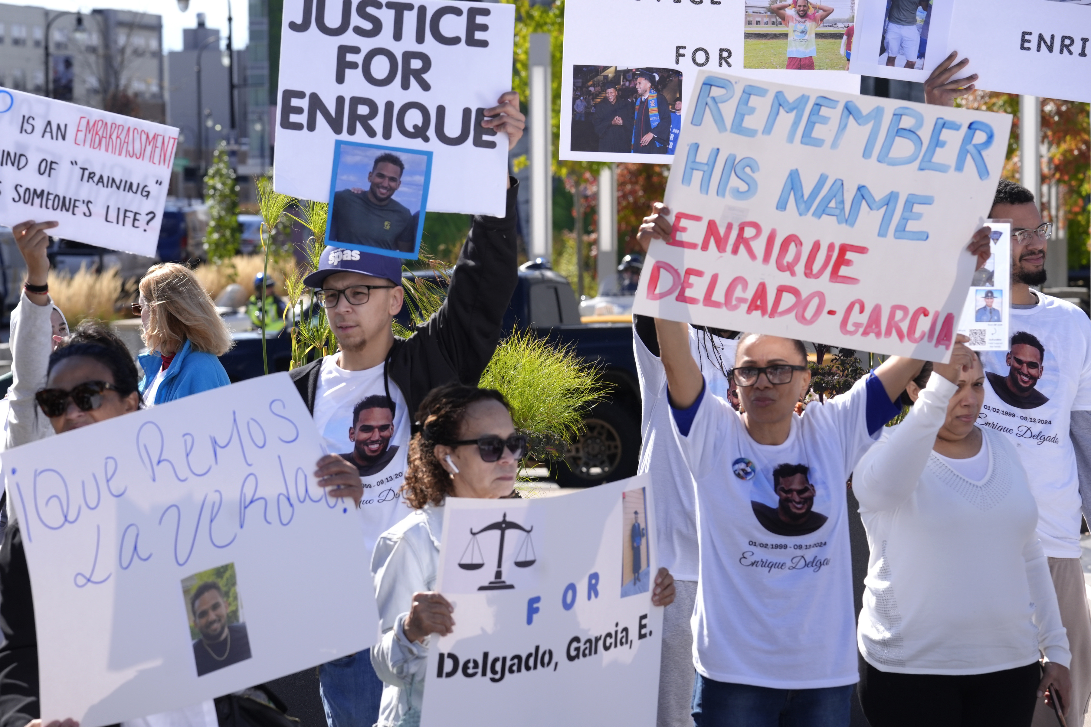 People display signs with with a likeness of Massachusetts State Police recruit Enrique Delgado-Garcia, who died following a State Police Academy training exercise, at a protest outside the State Police Academy graduation ceremony, Wednesday, Oct. 9, 2024, at the DCU Center, in Worcester, Mass. (AP Photo/Steven Senne)