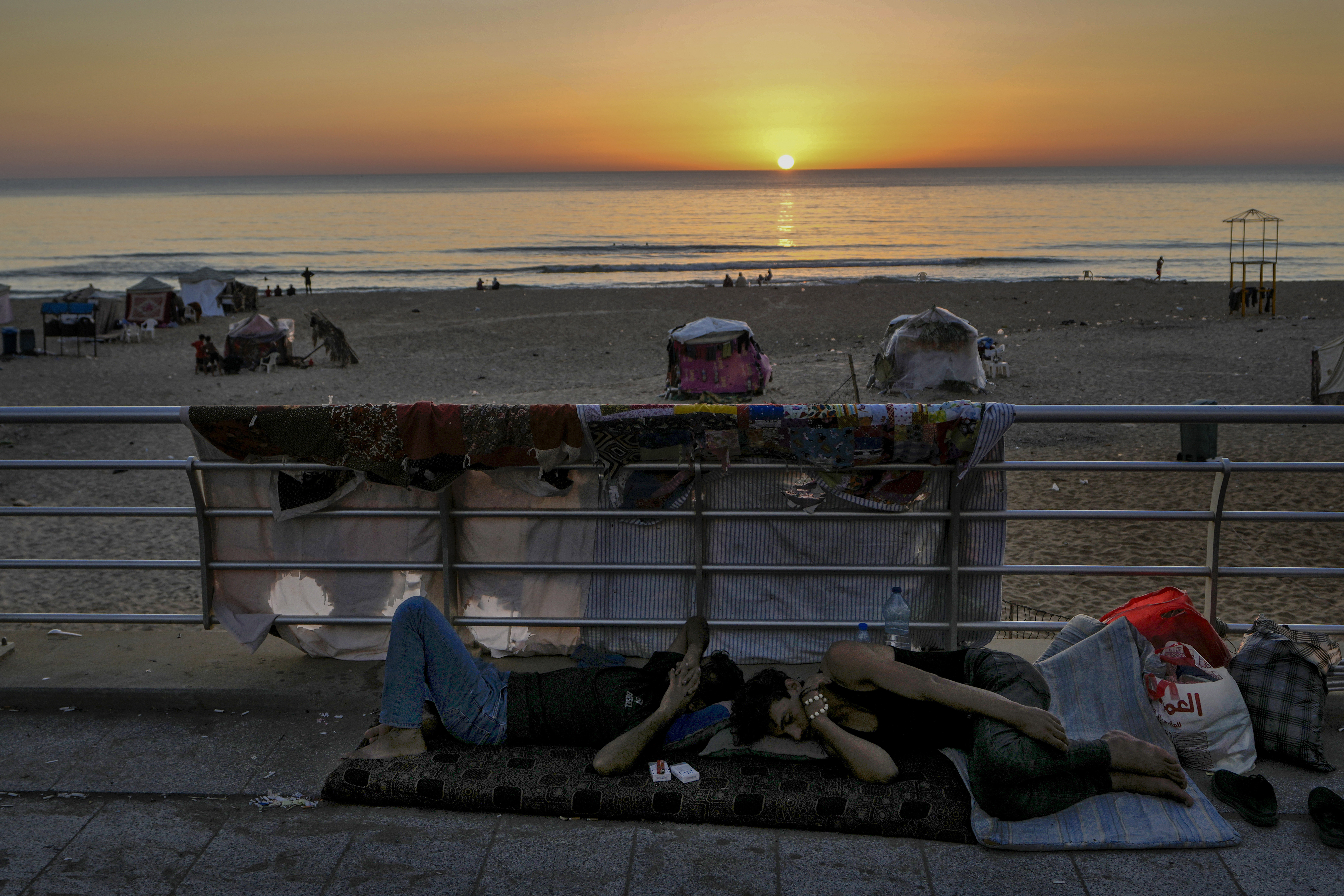 Men sleep at the Ramlet al-Baida public beach after fleeing the Israeli airstrikes in Dahiyeh, Beirut, Lebanon, Tuesday, Oct. 8, 2024. (AP Photo/Bilal Hussein)