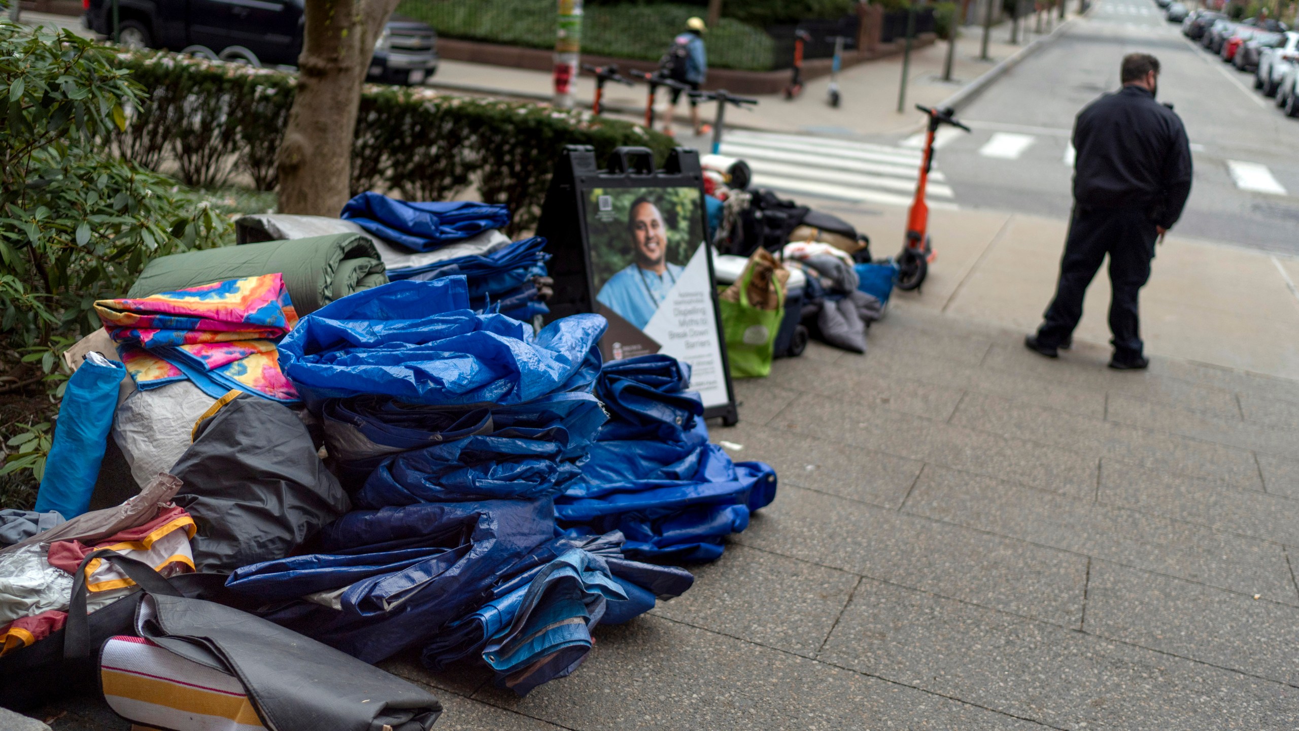 FILE - Tarps, sleeping bags and blankets sit piled on a sidewalk after an encampment protesting the Israel-Hamas war was taken down at Brown University as a campus security officer stands by, Tuesday, April 30, 2024, in Providence, R.I. (AP Photo/David Goldman, File)