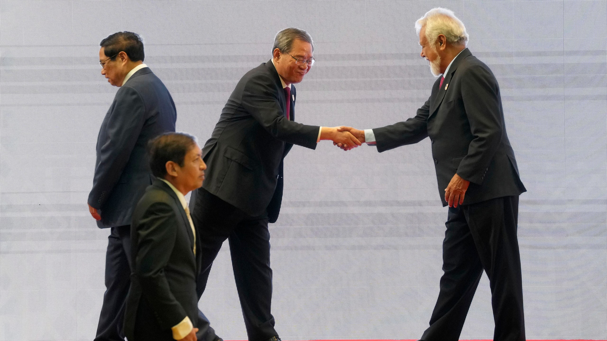 Chinese Premier Li Qiang, center, shakes hands with East Timor's Prime Minister Xanana Gusmao, right, as Vietnamese Prime Minister Pham Minh Chinh, left, and Myanmar's Foreign Ministry Permanent Secretary Aung Kyaw Moe, bottom, walk past by, during the 27th Association of Southeast Asian Nations (ASEAN)-China Summit in Vientiane, Laos, Thursday, Oct. 10, 2024. (AP Photo/Dita Alangkara)