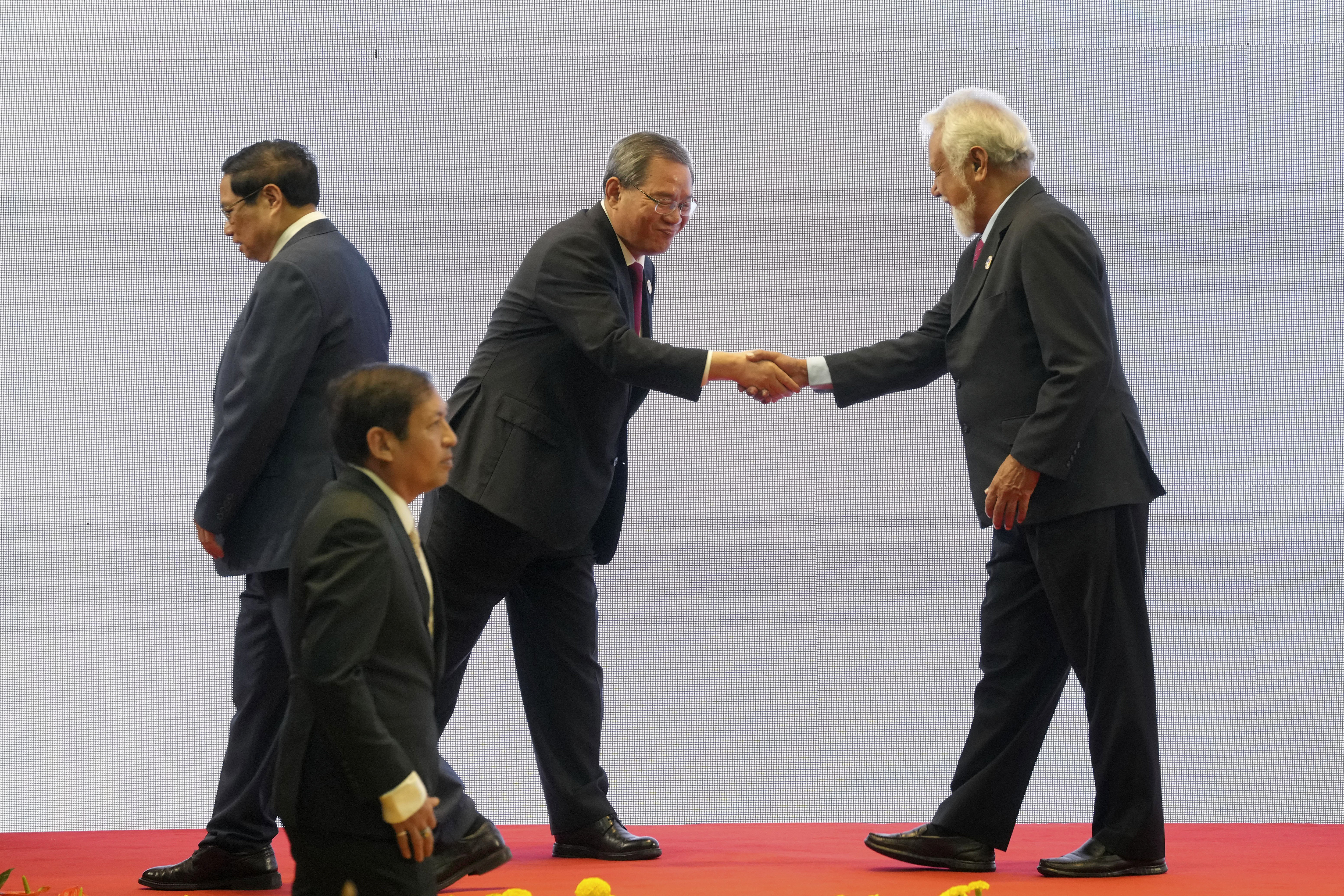 Chinese Premier Li Qiang, center, shakes hands with East Timor's Prime Minister Xanana Gusmao, right, as Vietnamese Prime Minister Pham Minh Chinh, left, and Myanmar's Foreign Ministry Permanent Secretary Aung Kyaw Moe, bottom, walk past by, during the 27th Association of Southeast Asian Nations (ASEAN)-China Summit in Vientiane, Laos, Thursday, Oct. 10, 2024. (AP Photo/Dita Alangkara)