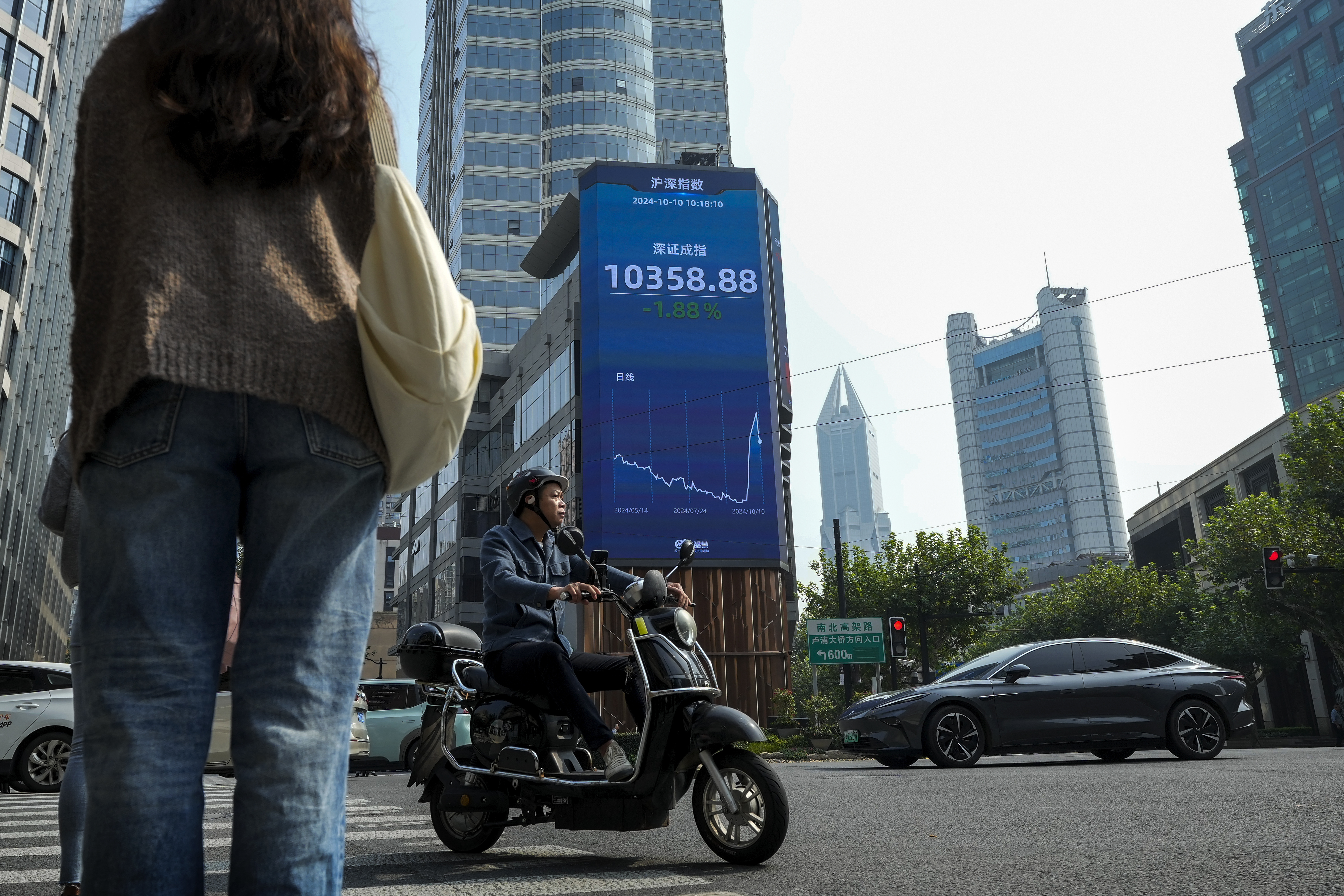 A motorist moves past an electronic board displaying Shenzhen shares trading index at a commercial office building in Shanghai, China, Thursday, Oct. 10, 2024. (AP Photo/Andy Wong)