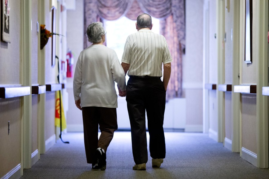 FILE - An elderly couple walks down a hall on Nov. 6, 2015 in Easton, Pa. (AP Photo/Matt Rourke, File)