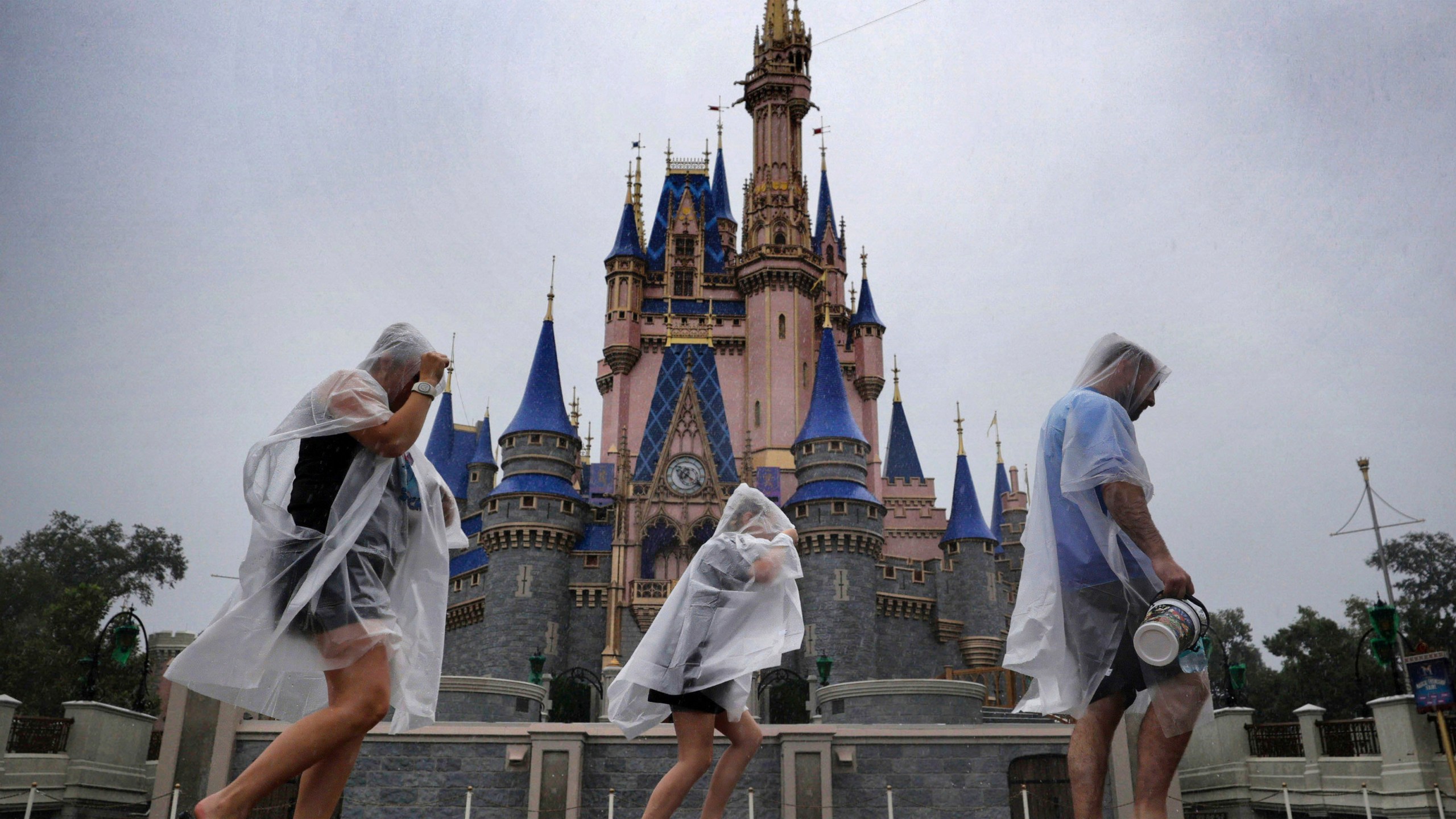 Guests weather early bands of rain from Hurricane Milton at the Magic Kingdom at Walt Disney World in Bay Lake, Fla., Wednesday, Oct. 9, 2024. All four of Disney's Florida theme parks closed early Wednesday due to the forecast track of the storm. (Joe Burbank/Orlando Sentinel via AP)