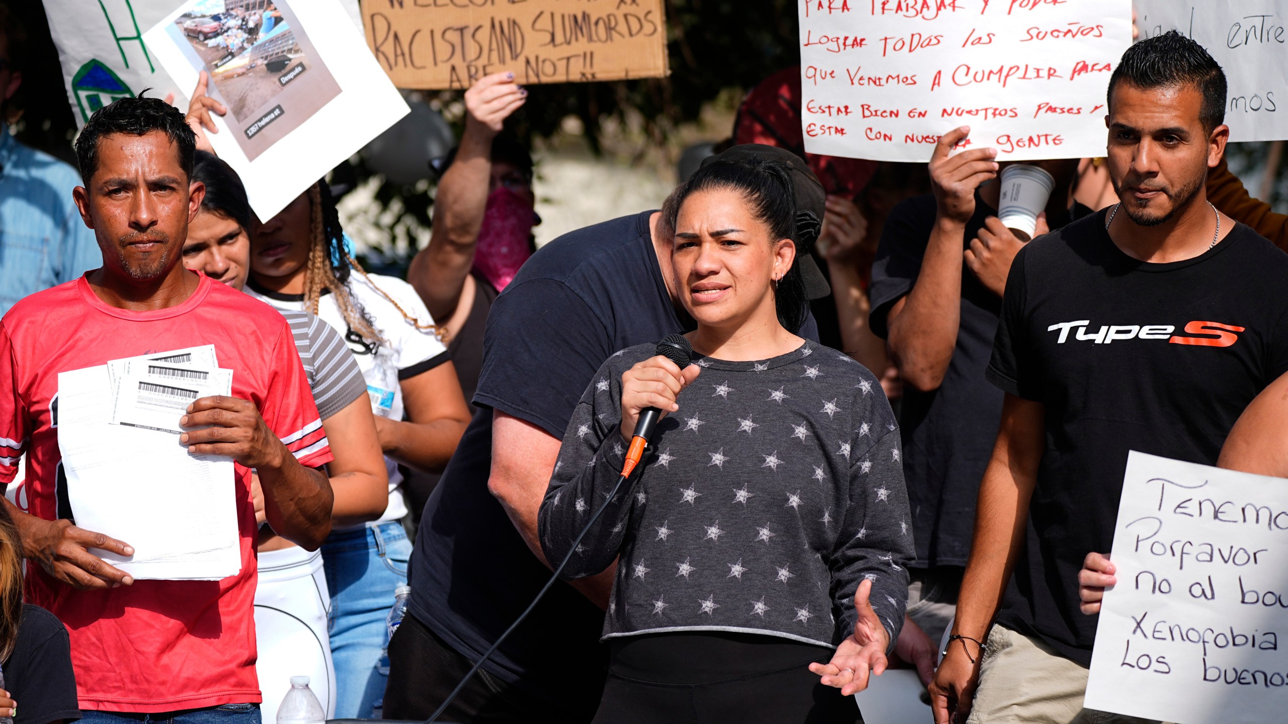 FILE - Juan Carlos Jimenez, left, listens as Geraldine Massa speaks during a rally staged by the East Colfax Community Collective to address chronic problems in the apartment buildings occupied by people displaced from their home countries in central and South America, Sept. 3, 2024, in Aurora, Colo. (AP Photo/David Zalubowski, File)