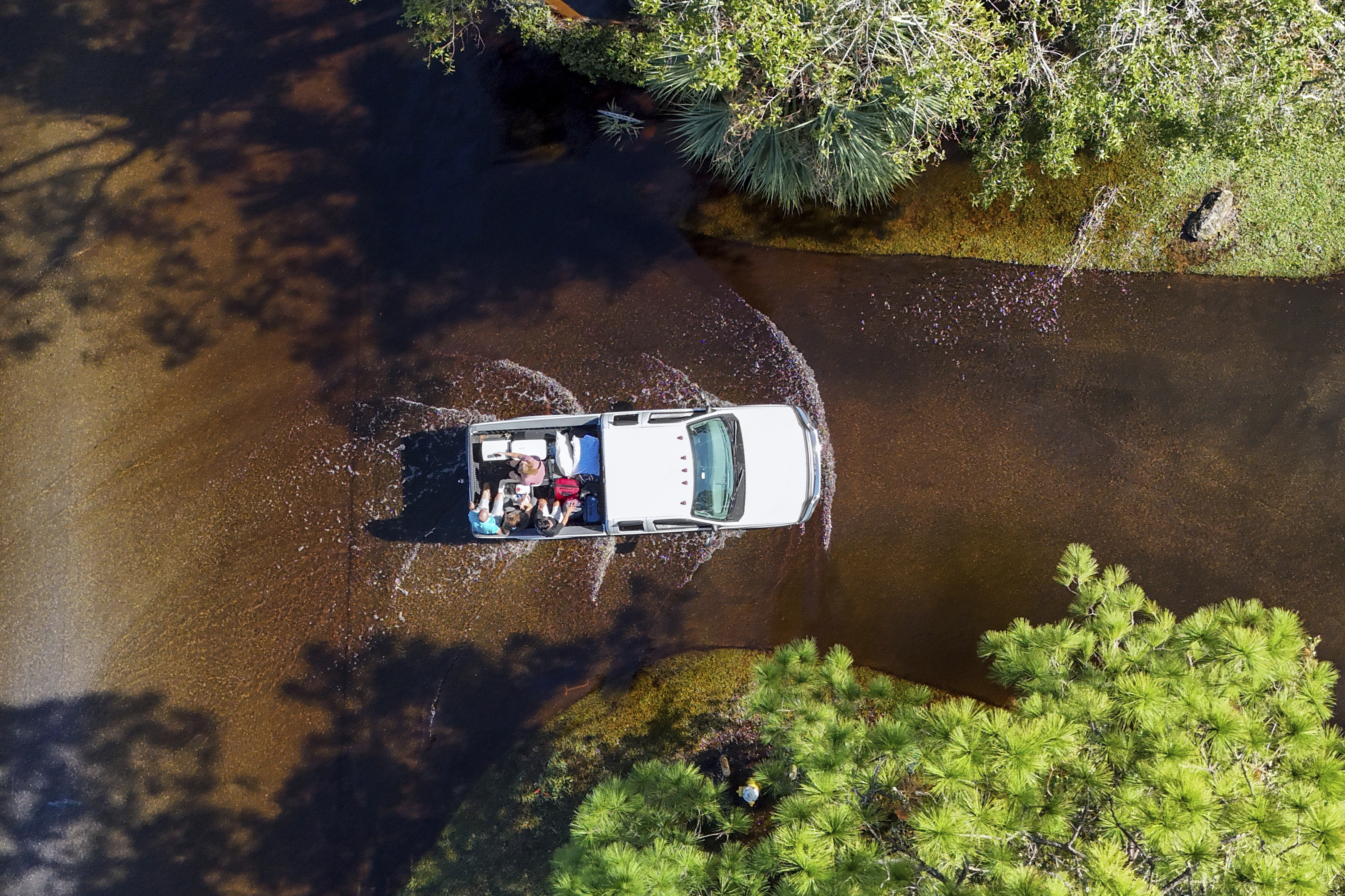 Two couples who evacuated get a ride back to their home through flooding after Hurricane Milton hit the region, Thursday, Oct. 10, 2024, in Palm Harbor, Fla. (AP Photo/Mike Carlson)