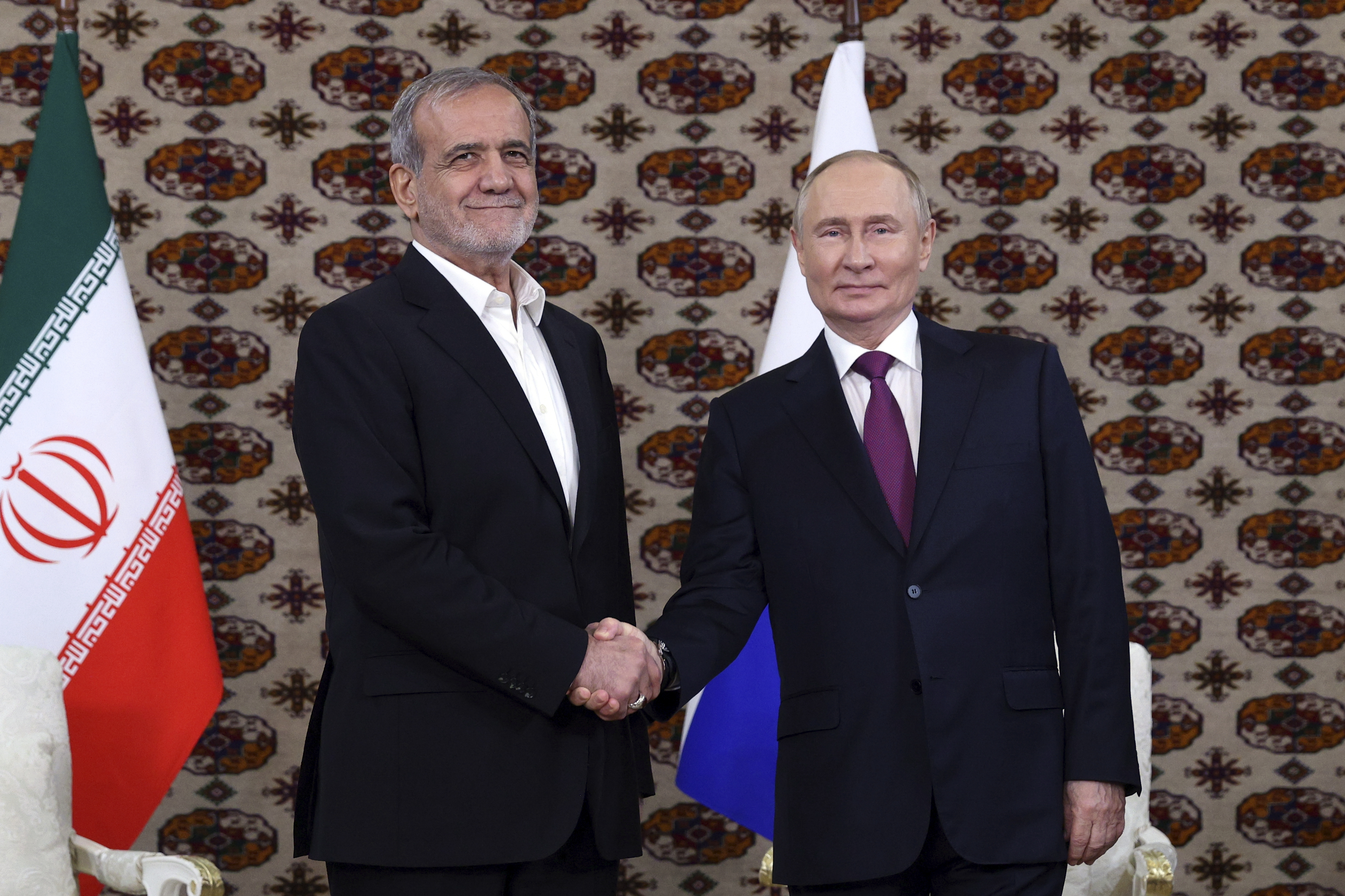 Russian President Vladimir Putin, right, and Iranian President Masoud Pezeshkian shake hands during their meeting on the sidelines of the International Forum "The Interconnection of Times and Civilizations – the basis of peace and development" dedicated to the 300th anniversary of the birth of the outstanding Turkmen poet and thinker Magtymguly Fragi in Ashgabat, Turkmenistan, Friday, Oct. 11, 2024. (Alexander Shcherbak, Sputnik, Kremlin Pool Photo via AP)