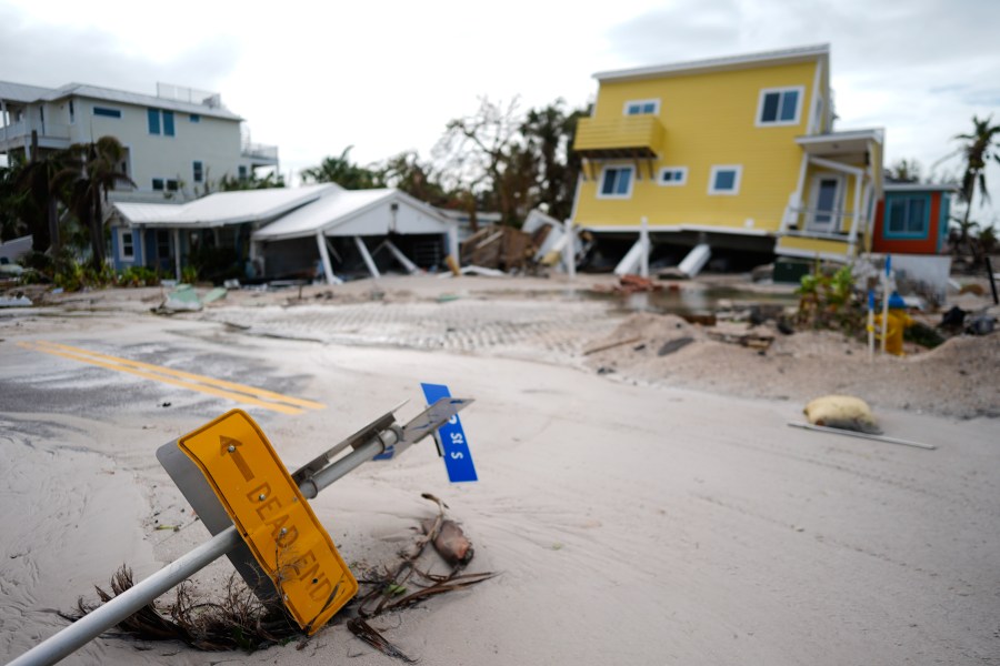 A house sits toppled off its stilts after the passage of Hurricane Milton, alongside an empty lot where a home was swept away by Hurricane Helene, in Bradenton Beach on Anna Maria Island, Fla., Thursday, Oct. 10, 2024. (AP Photo/Rebecca Blackwell)