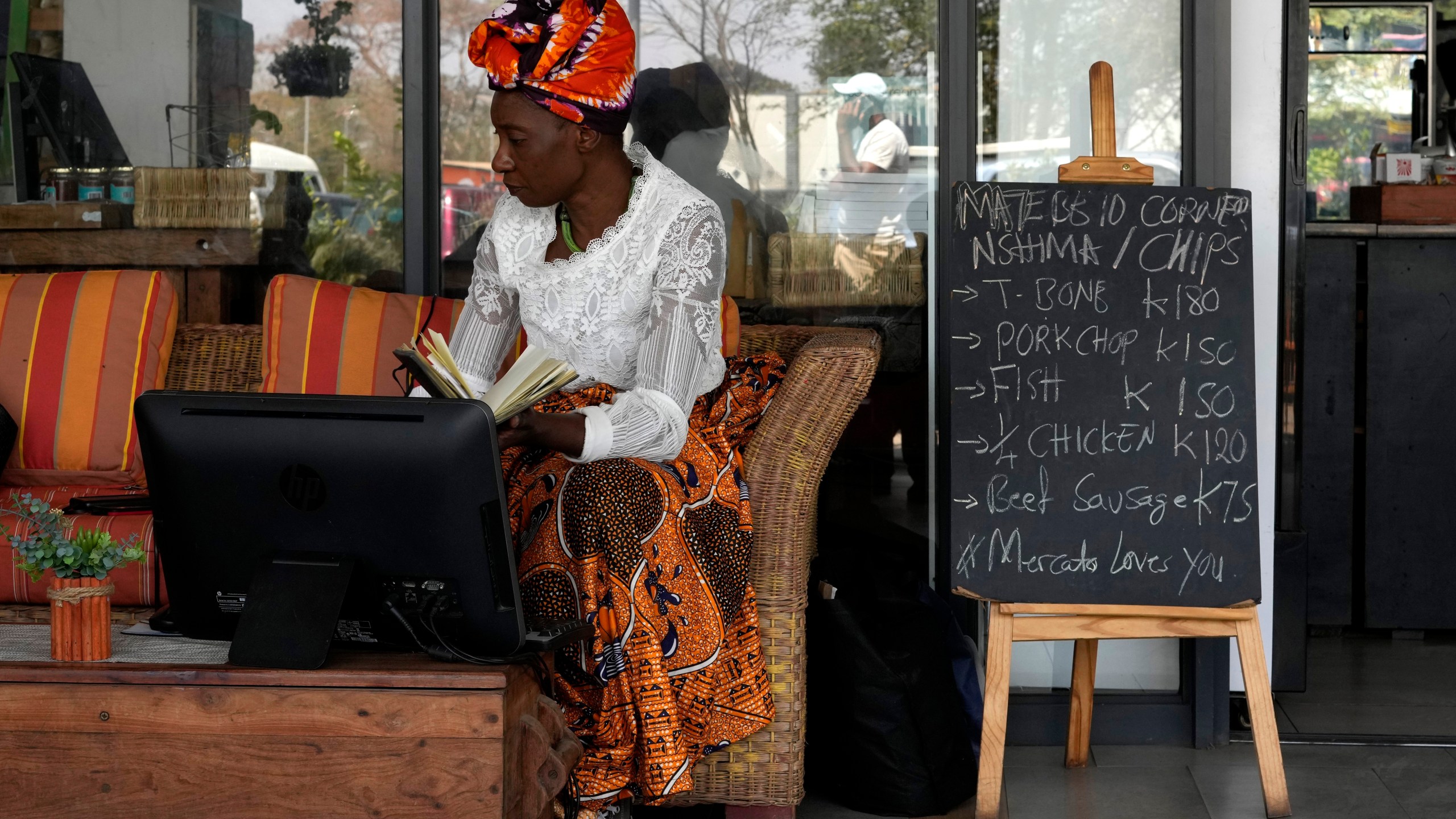 Edla Musonda works on her desktop computer at Mercato Cafe in Lusaka, Zambia, Tuesday, Sept. 17, 2024. (AP Photo/Themba Hadebe)