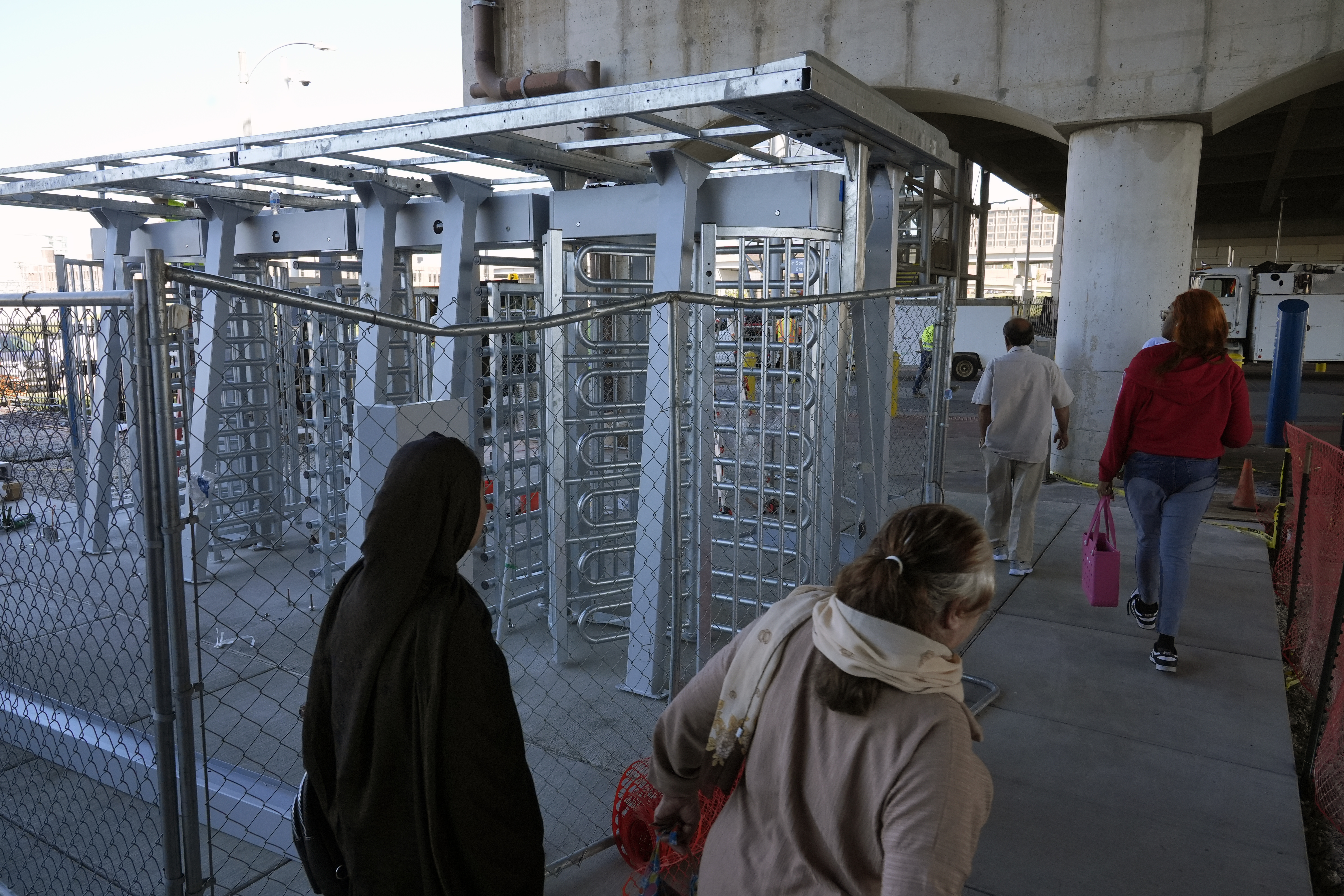 Riders walk around metal gates being installed that will prevent customers from entering a MetroLink platform without a valid fare card Wednesday, Oct. 9, 2024, in St. Louis. (AP Photo/Jeff Roberson)