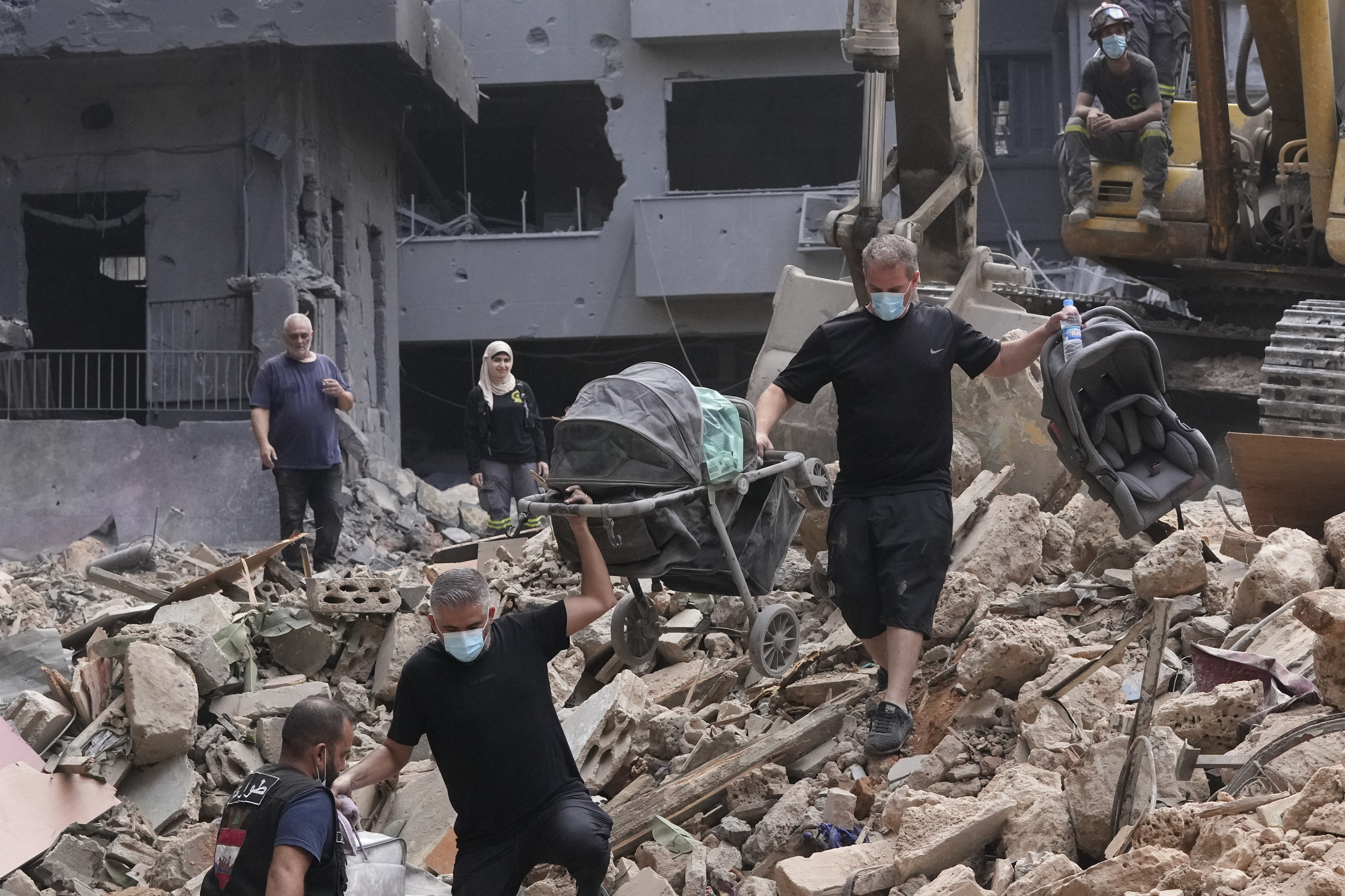 Residents of a building damaged in an Israeli airstrike return to collect their family's belongings at the site of Thursday's Israeli airstrike in Beirut, Lebanon, Saturday, Oct. 12, 2024. (AP Photo/Hassan Ammar)