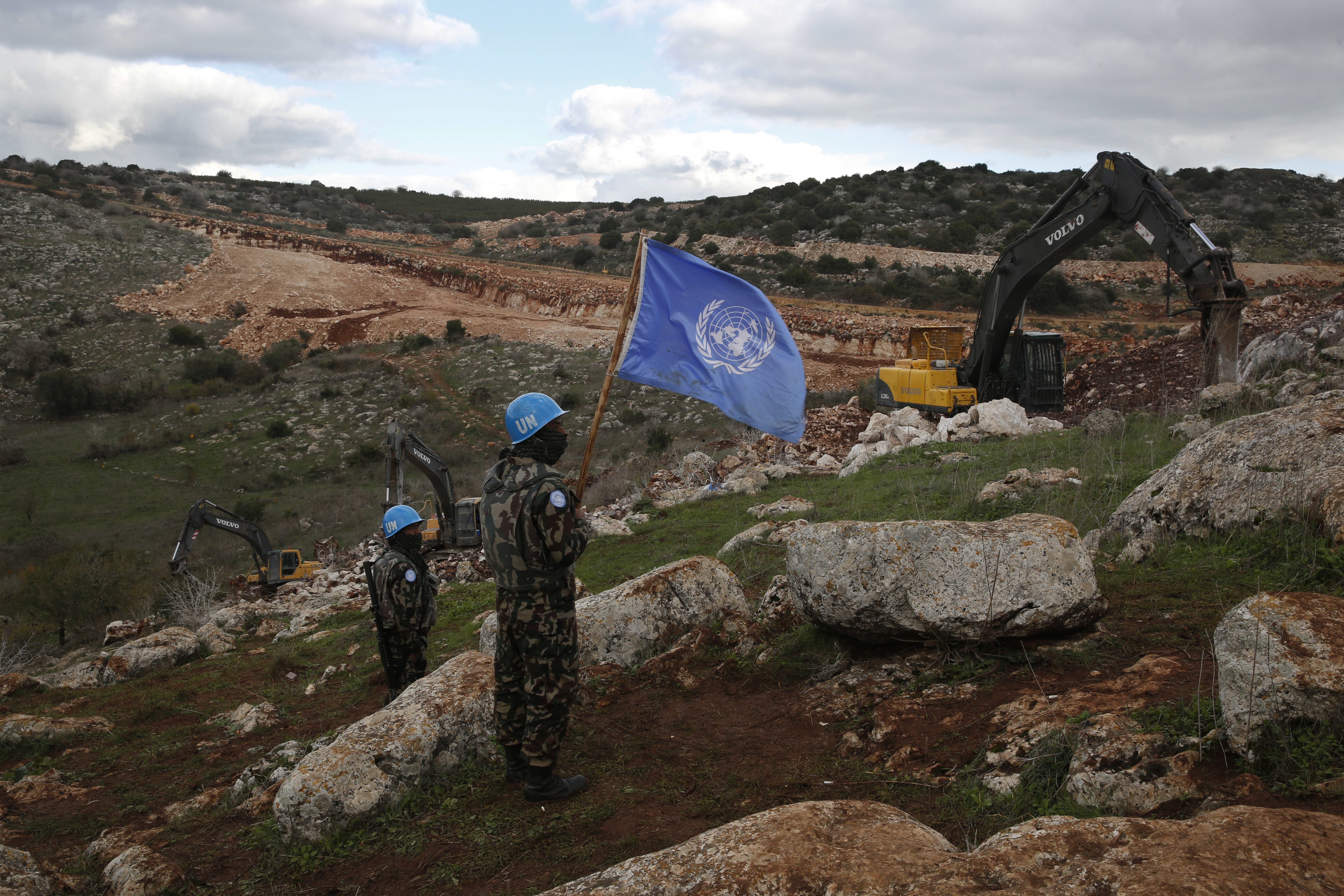 FILE - UN peacekeepers hold their flag, as they observe Israeli excavators attempt to destroy tunnels built by Hezbollah, near the southern Lebanese-Israeli border village of Mays al-Jabal, Lebanon, Dec. 13, 2019. (AP Photo/Hussein Malla, File)