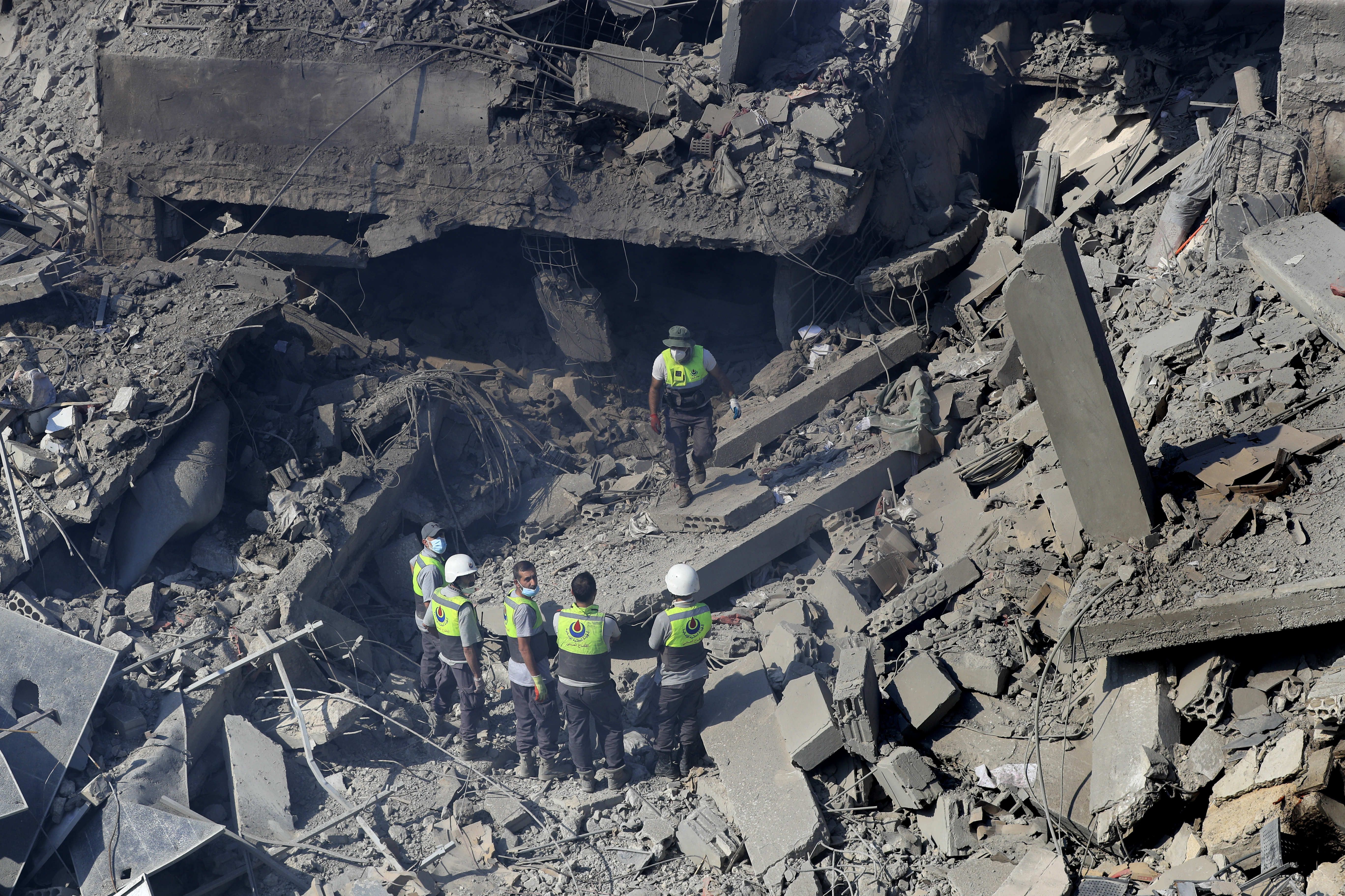 Hezbollah rescue workers stand on the rubble of destroyed buildings at commercial street that was hit Saturday night by Israeli airstrikes, in NAbatiyeh town, south Lebanon, Sunday, Oct. 13, 2024. (AP Photo/Mohammed Zaatari)