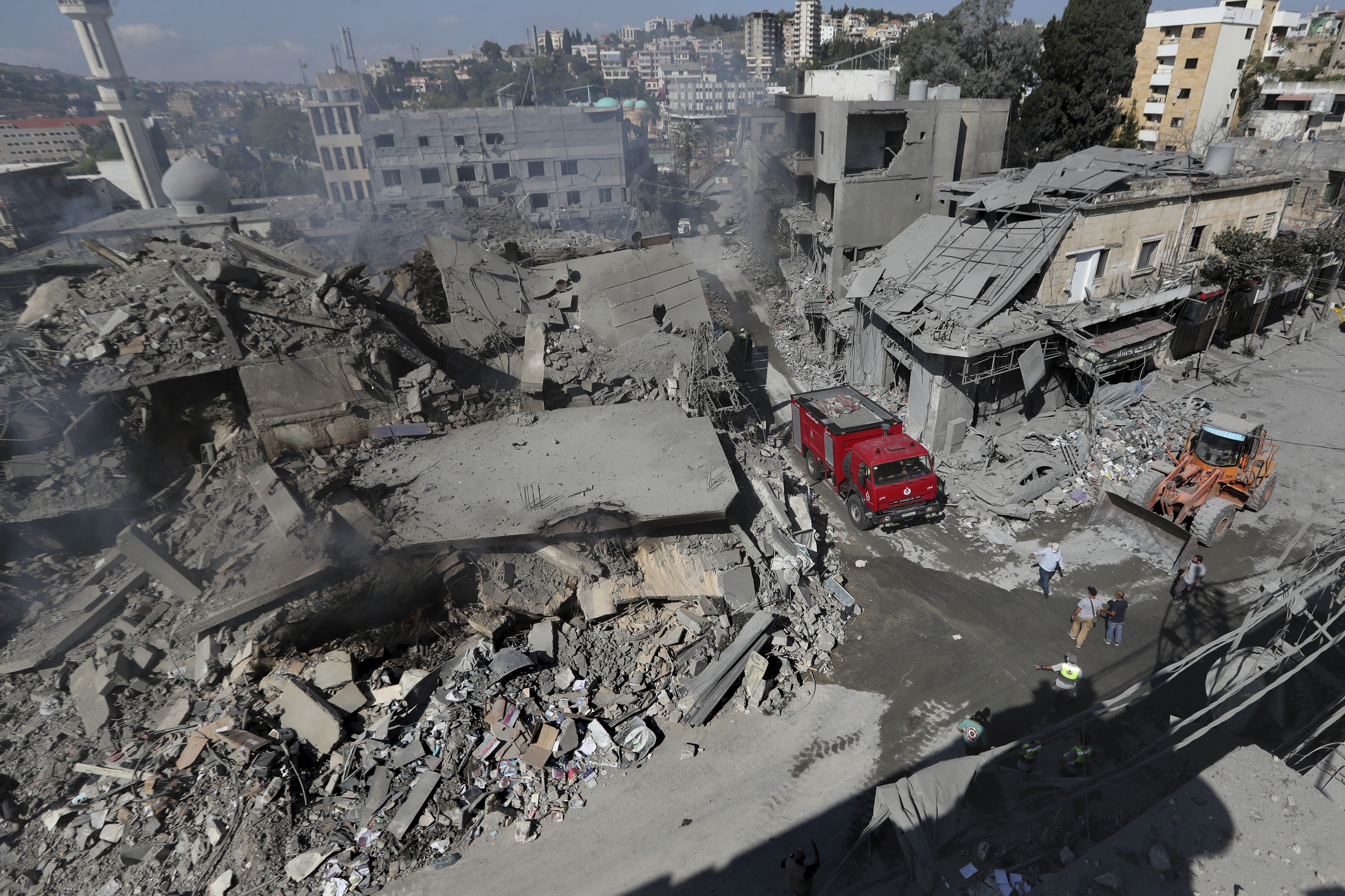 Hezbollah rescue workers use a bulldozer to remove the rubble of destroyed buildings on a commercial street that was hit Saturday night by Israeli airstrikes, in Nabatiyeh town, south Lebanon, Sunday, Oct. 13, 2024. (AP Photo/Mohammed Zaatari)