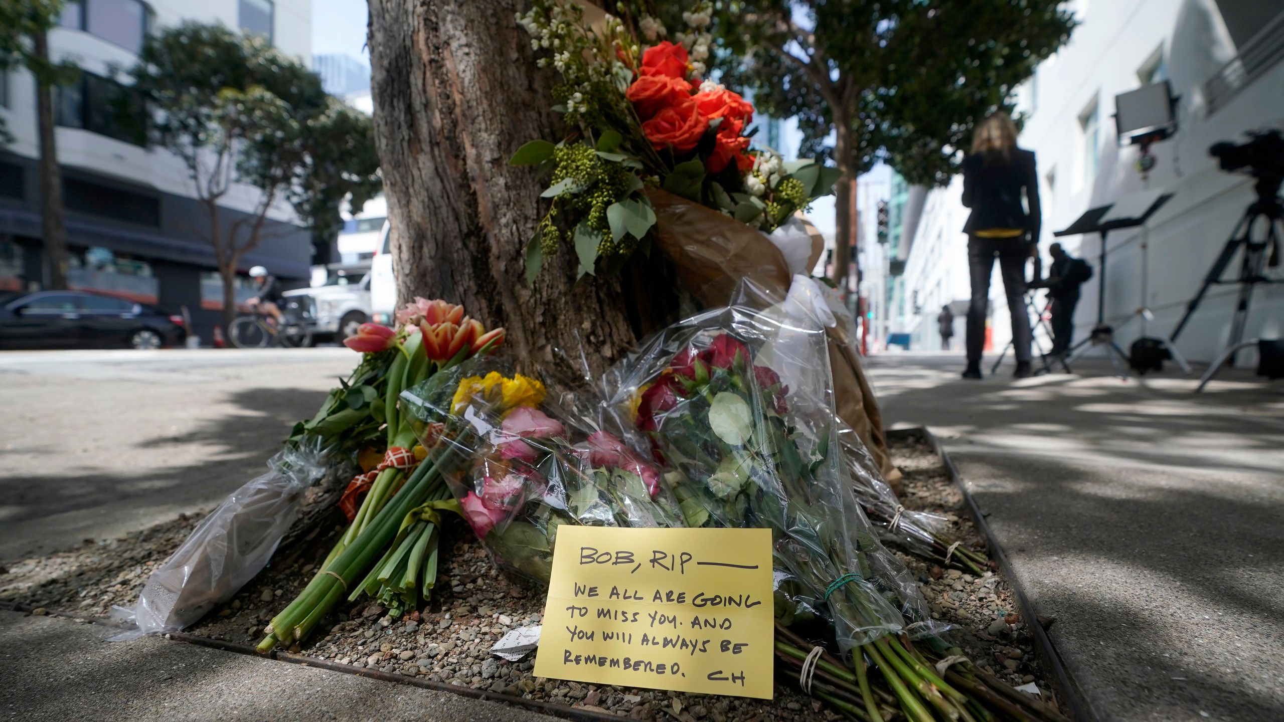 FILE - Flowers sit at a tree in front of the building where a technology executive was fatally stabbed outside of in San Francisco, April 6, 2023. (AP Photo/Jeff Chiu, File)