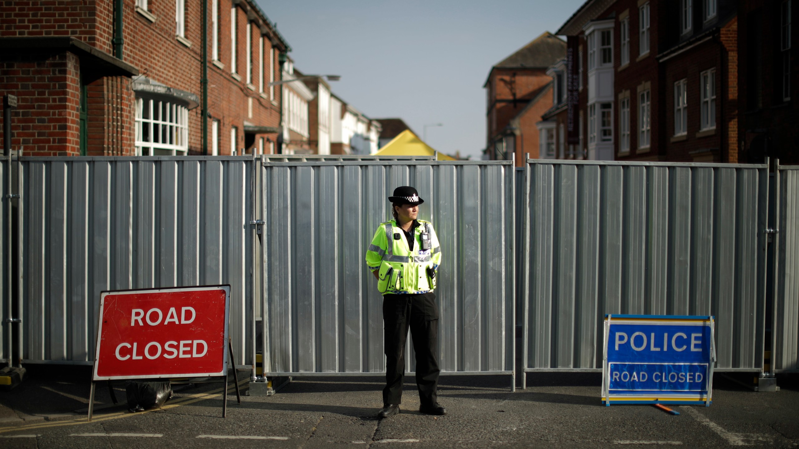 FILE - A police officer guards metal fencing erected on the end of Rollestone Street, the location of the John Baker House for homeless people, in Salisbury, England, Thursday, July 5, 2018. (AP Photo/Matt Dunham, File)