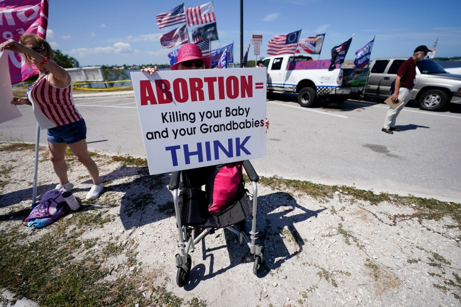 FILE - Leona Mangan of Lakeworth, Fla., holds a sign as she gathers with other supporters of former President Donald Trump outside his Mar-a-Lago estate in West Palm Beach, Fla., March 21, 2023. (AP Photo/Gerald Herbert, file)