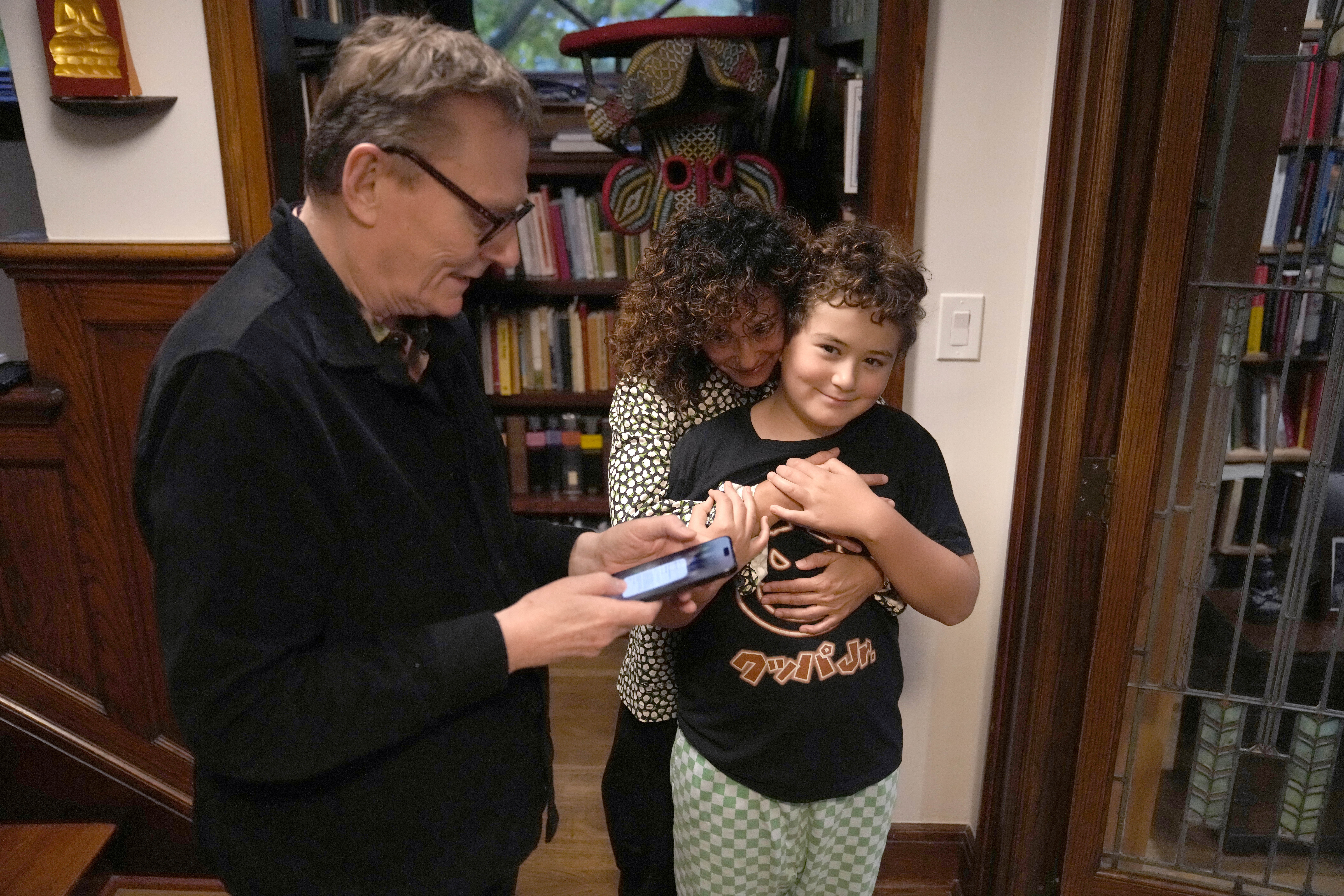 Nobel prize winner in Economics, James A. Robinson, looks over a selfie he made for the Nobel Foundation with his wife Dr. Maria Angelica Bautista, and son Adrian at their home in the Hyde Park neighborhood of Chicago, Monday, Oct. 14, 2024. (AP Photo/Charles Rex Arbogast)